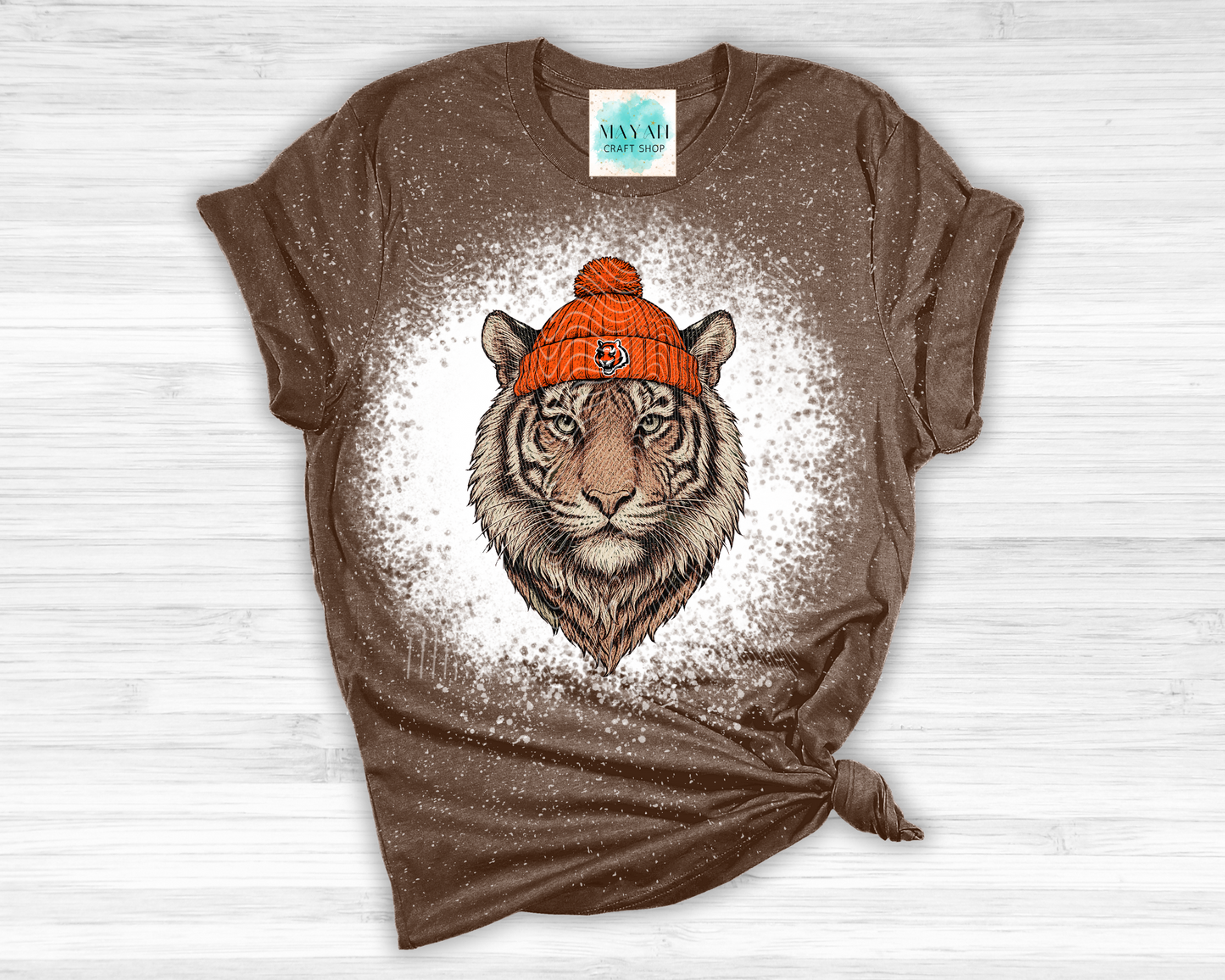 Brown t-shirt with a tiger wearing an orange beanie on a white background