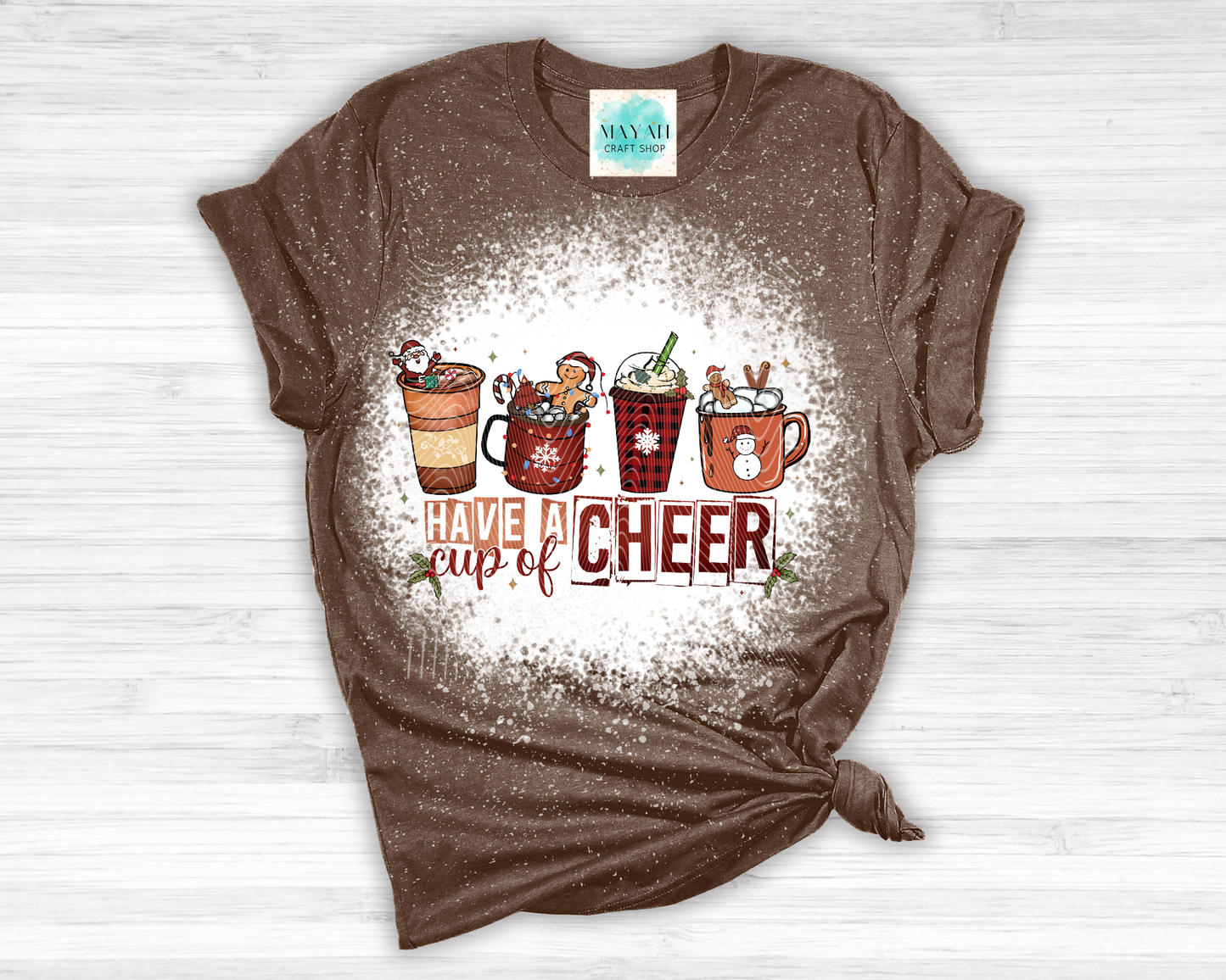 Brown t-shirt with Christmas-themed design on a white wooden surface