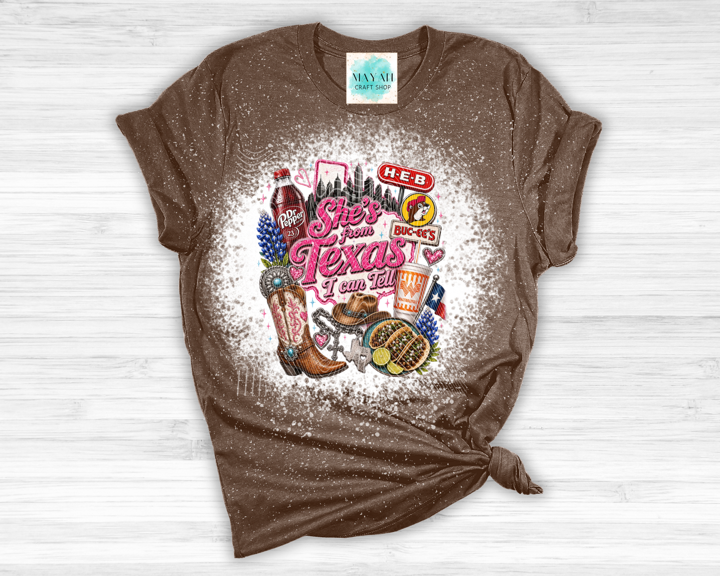 Brown t-shirt with Texas-themed graphics and text on a white wooden surface