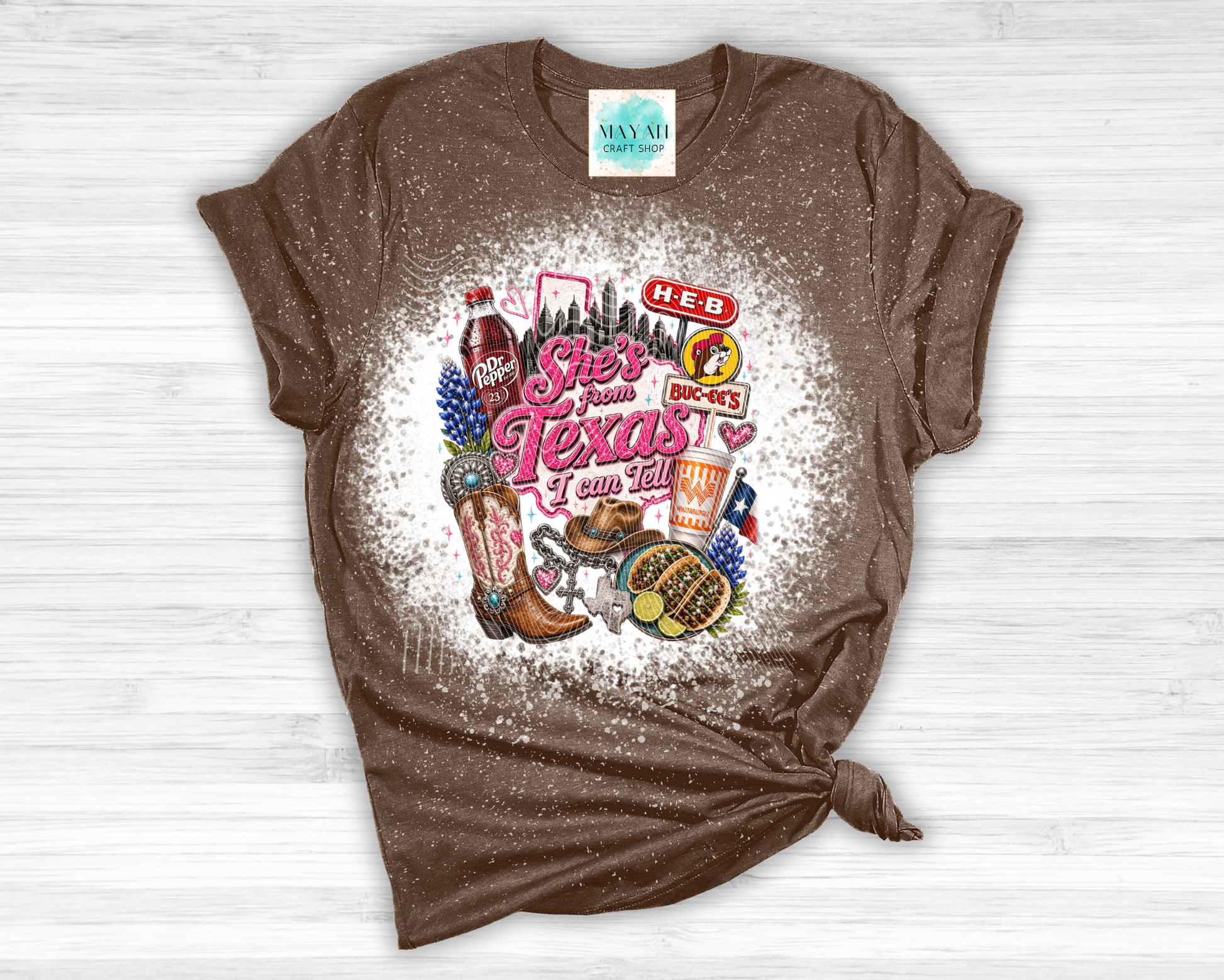 Brown t-shirt with Texas-themed graphics and text on a white wooden surface
