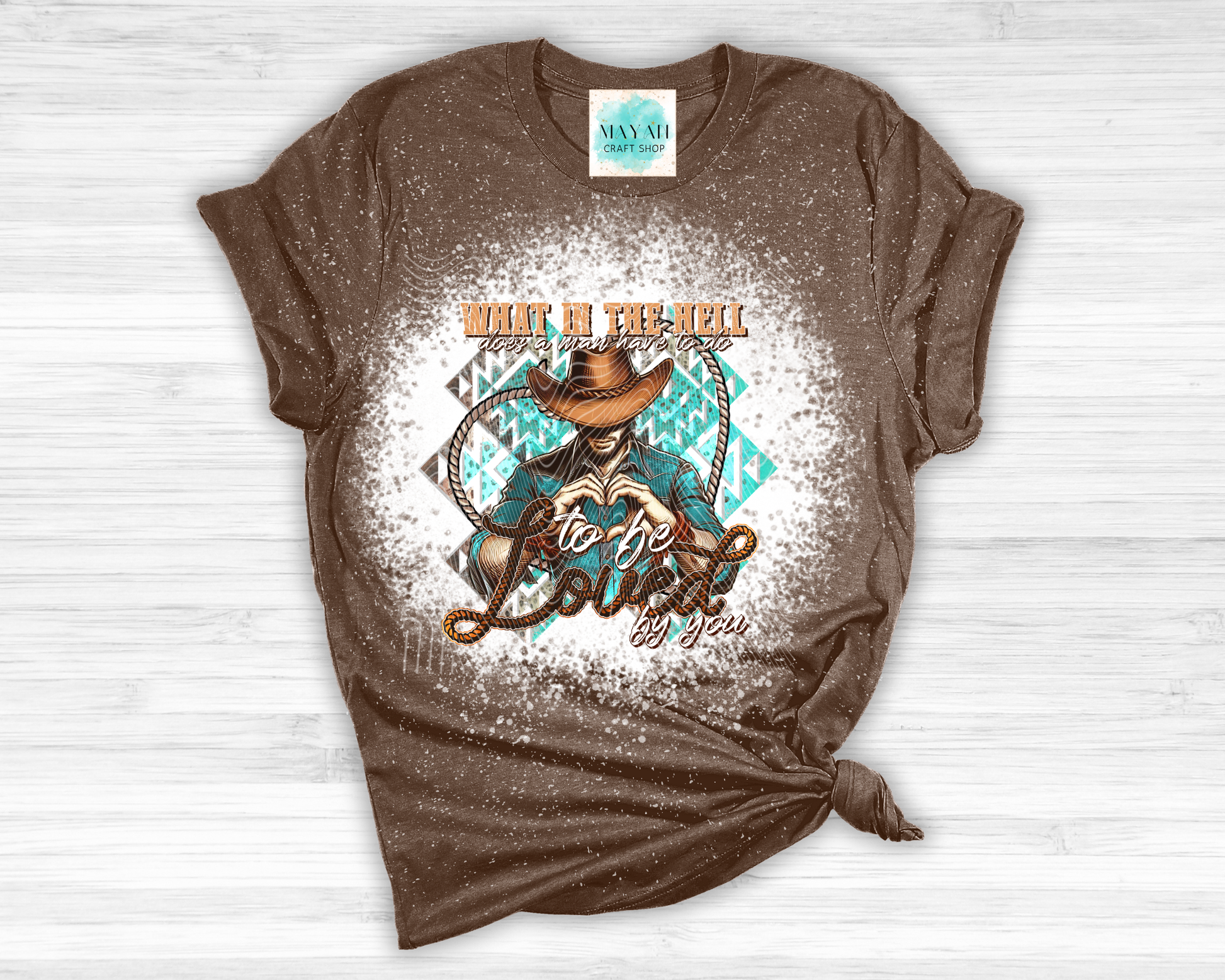 Brown t-shirt with graphic design and text on a white wooden surface