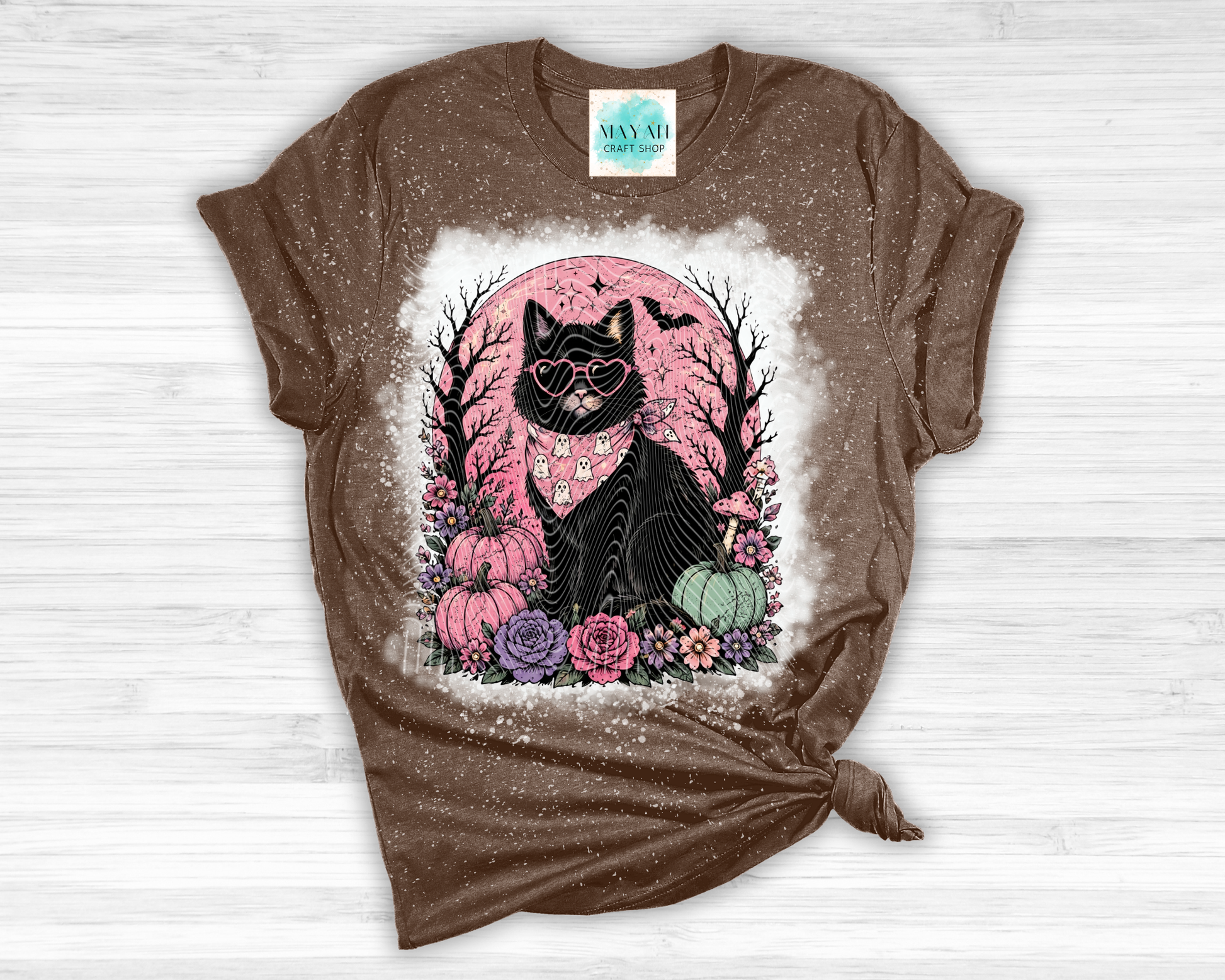 Brown t-shirt with a black cat graphic on a white wooden background