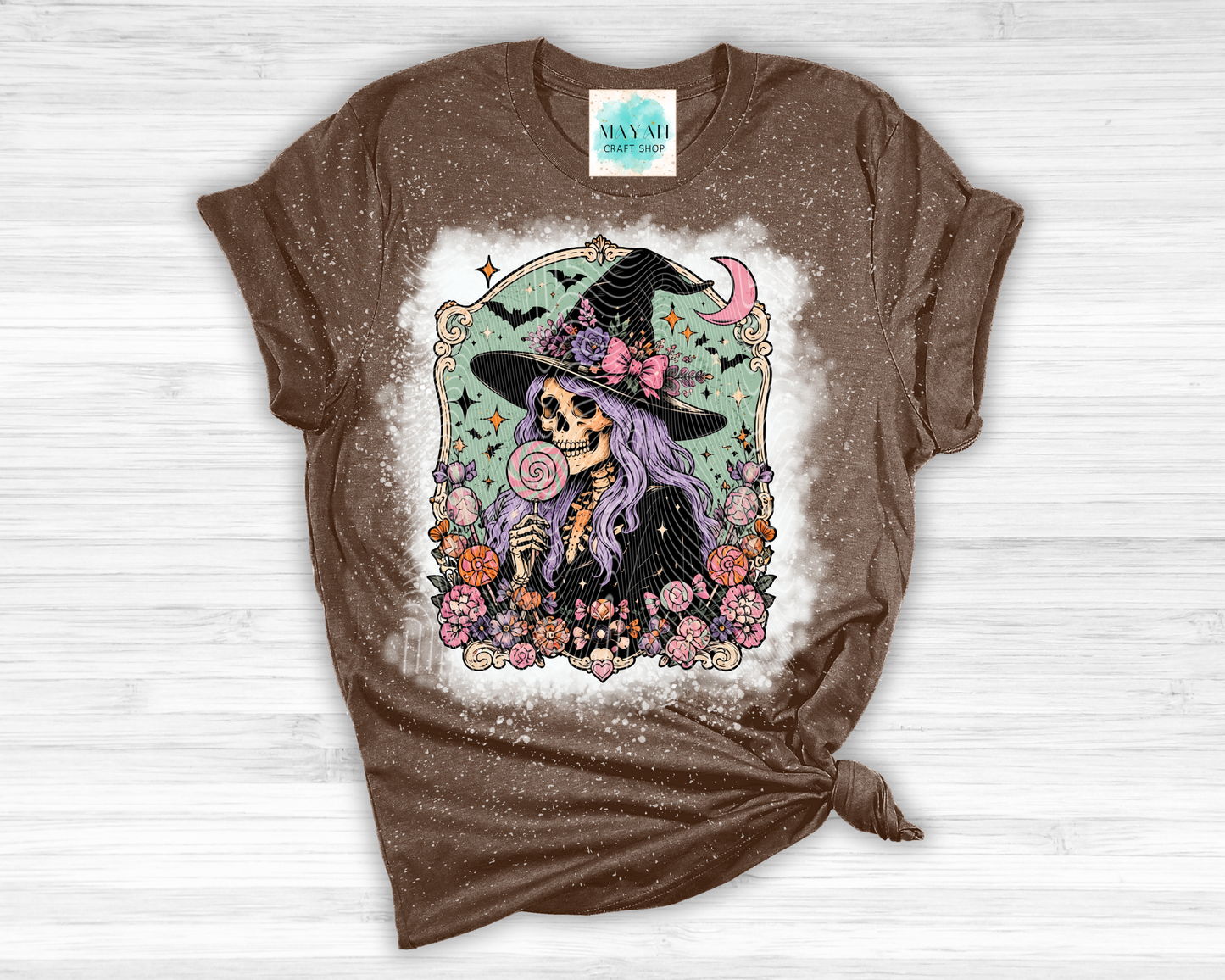 Brown t-shirt with a colorful graphic of a skeleton witch on a white background