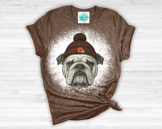 Brown t-shirt with a graphic of a dog wearing a hat on a white wooden surface