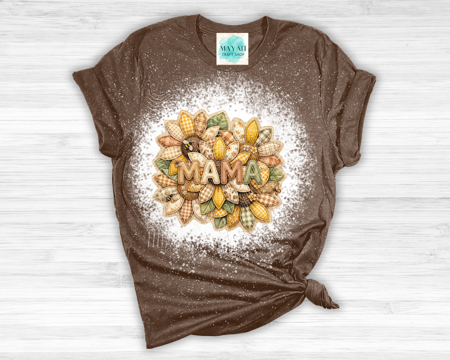 Brown t-shirt with 'MAMA' and corn design on a white wooden surface