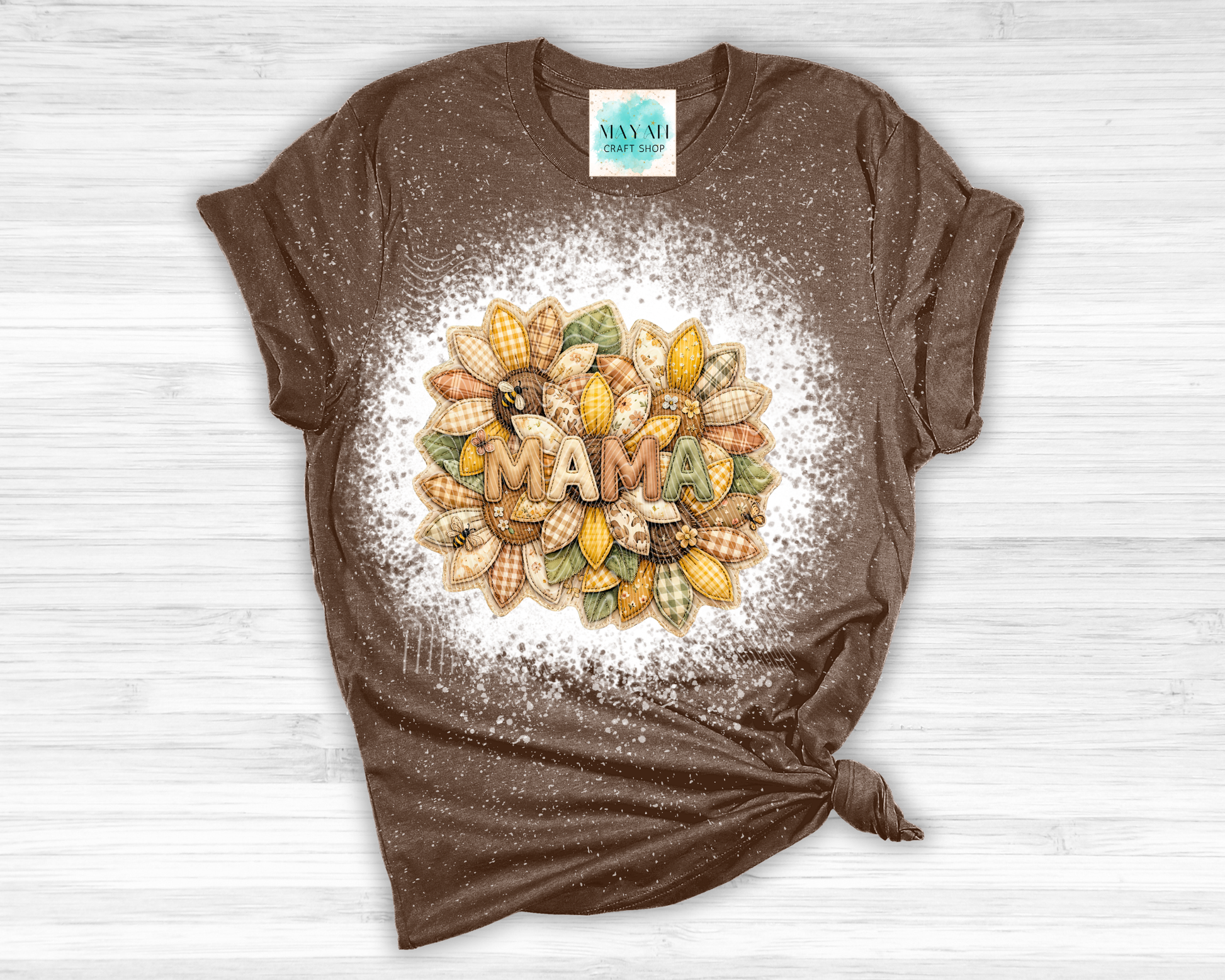 Brown t-shirt with 'MAMA' and corn design on a white wooden surface