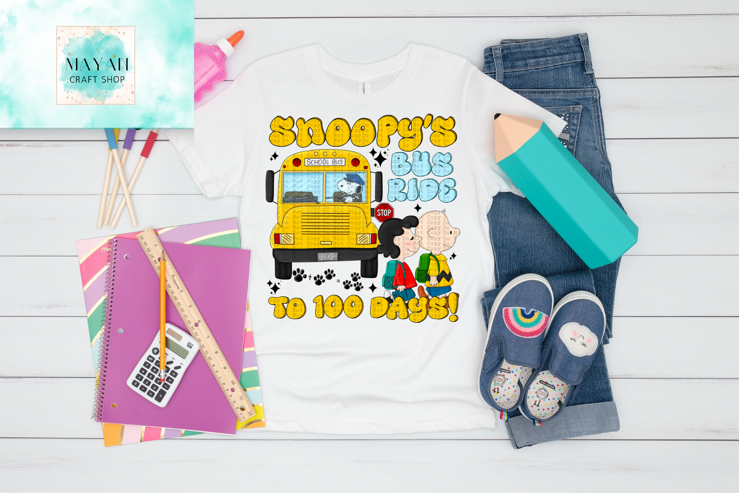 Children's t-shirt with dog design, school supplies, and shoes on a wooden surface.