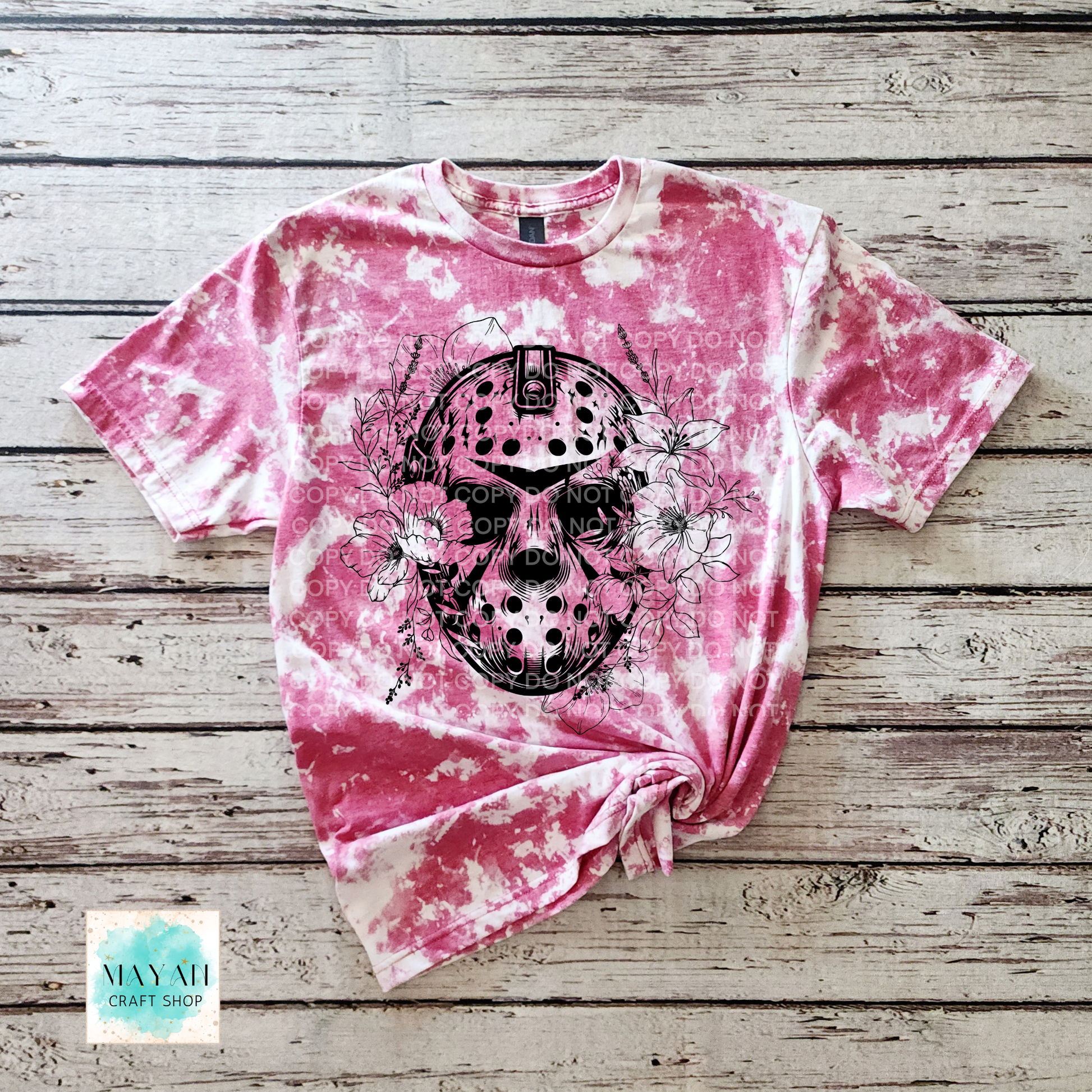 Pink tie-dye t-shirt with a black graphic design on a wooden surface