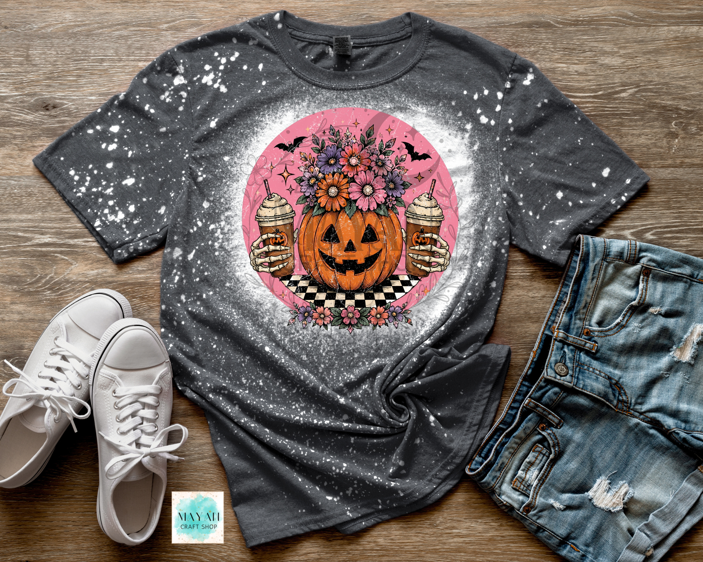 Gray t-shirt with Halloween-themed design on a wooden surface with shoes and jeans.