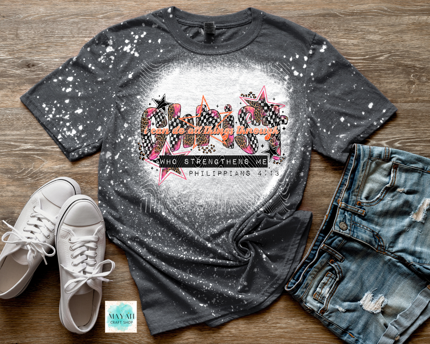 Gray bleached t-shirt with graphic design on a wooden surface, accompanied by white sneakers and blue jeans.