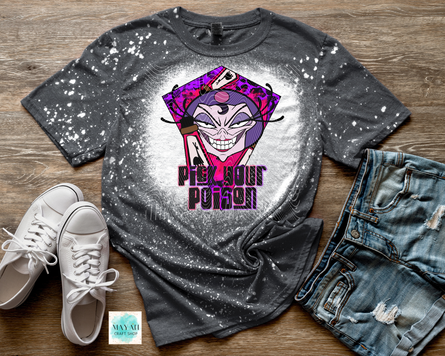 Gray t-shirt with a graphic design of a character and text, paired with white sneakers and denim shorts on a wooden surface.