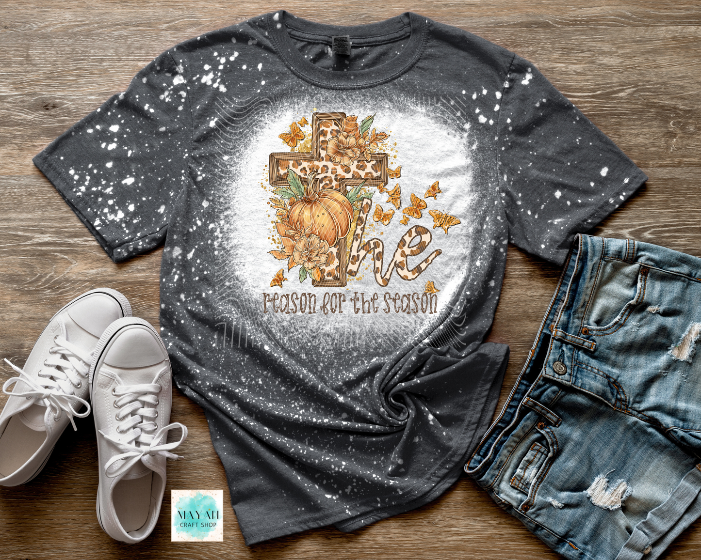 Gray bleached t-shirt with autumn design and text, paired with white sneakers and jeans on a wooden surface.