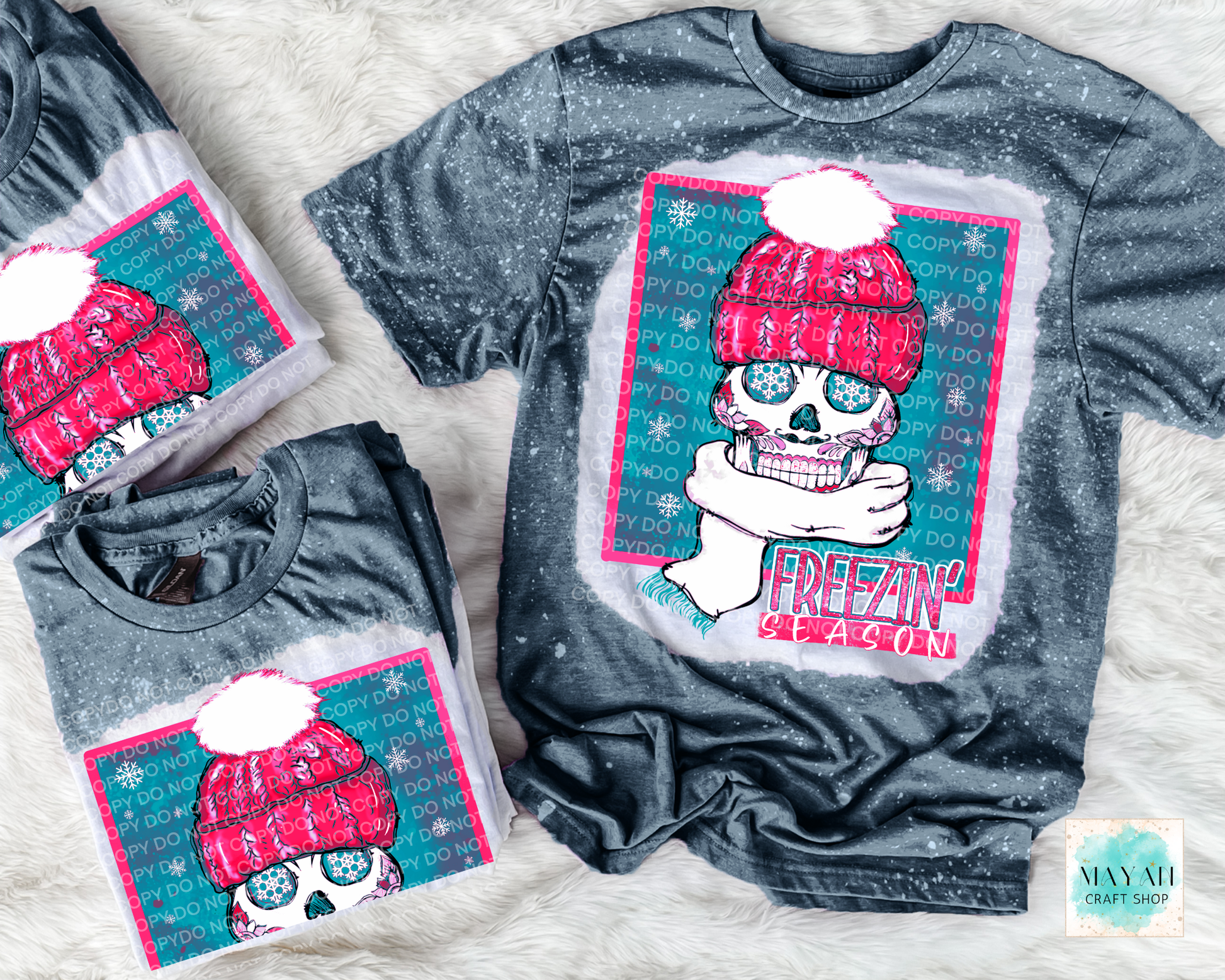 Gray t-shirt with a colorful graphic design featuring a skull wearing a pink hat and scarf, on a textured surface.