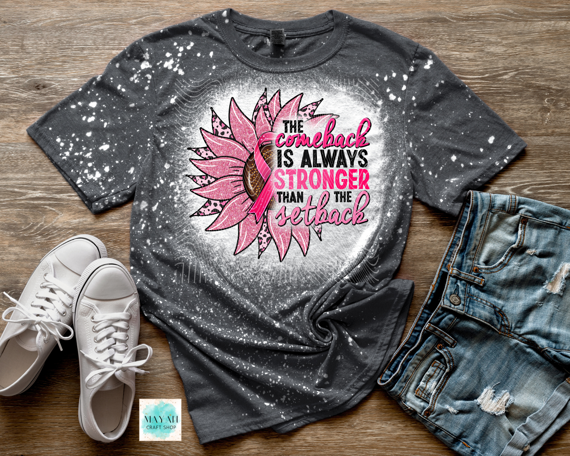 Gray t-shirt with pink sunflower design and text on a wooden surface with white sneakers and jeans.