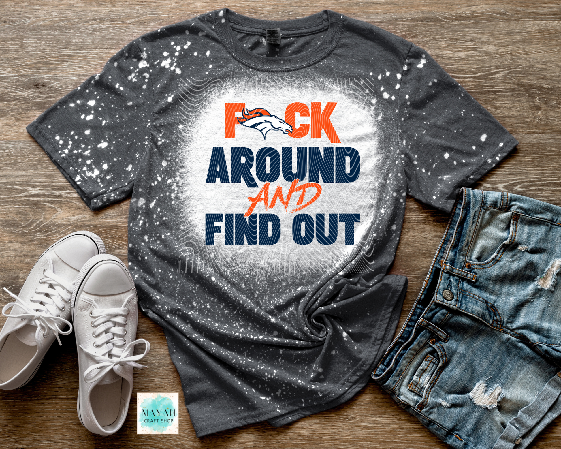 Gray t-shirt with colorful text, white sneakers, and jeans on a wooden surface