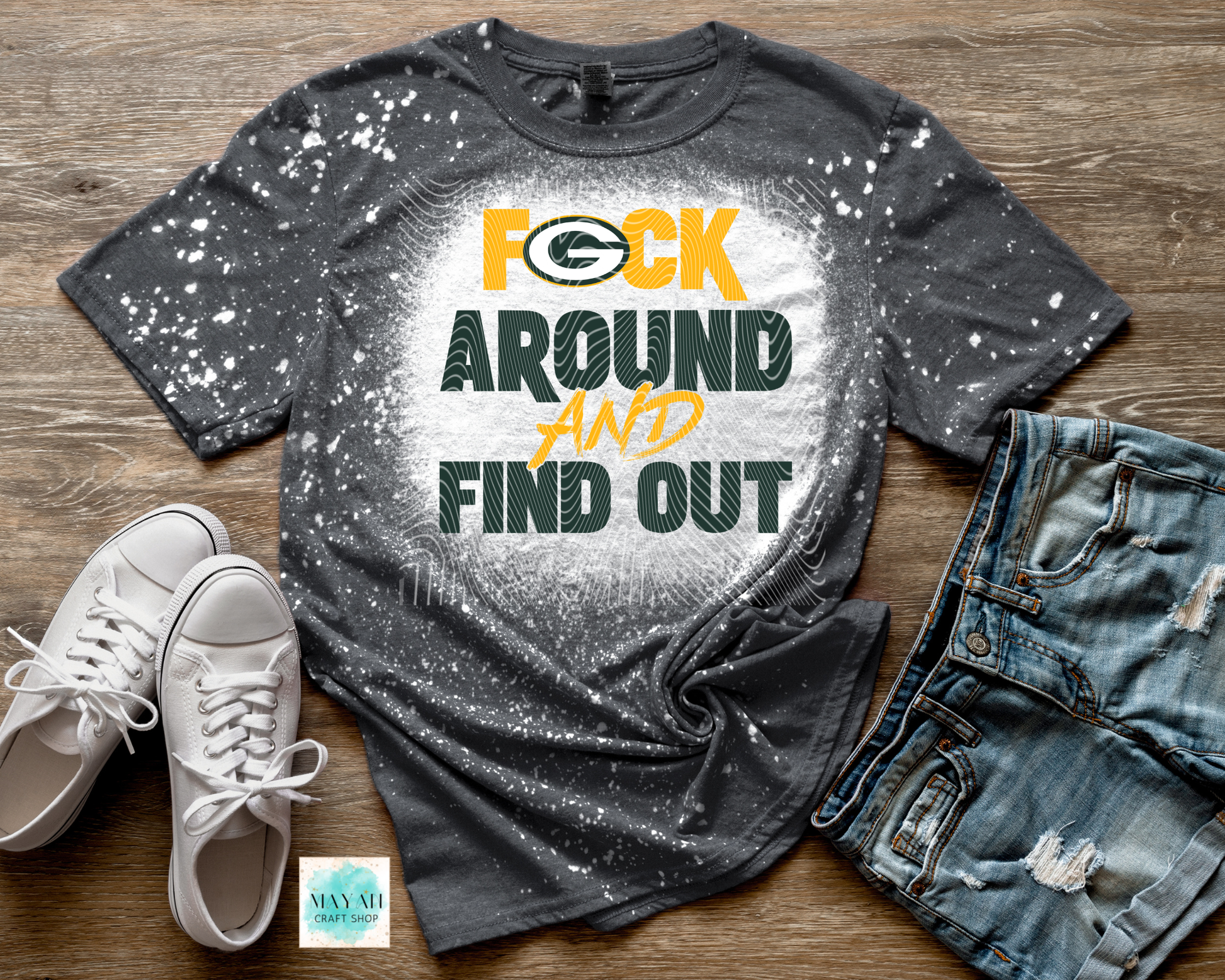 Gray t-shirt with graphic text, white sneakers, and distressed jeans on a wooden surface