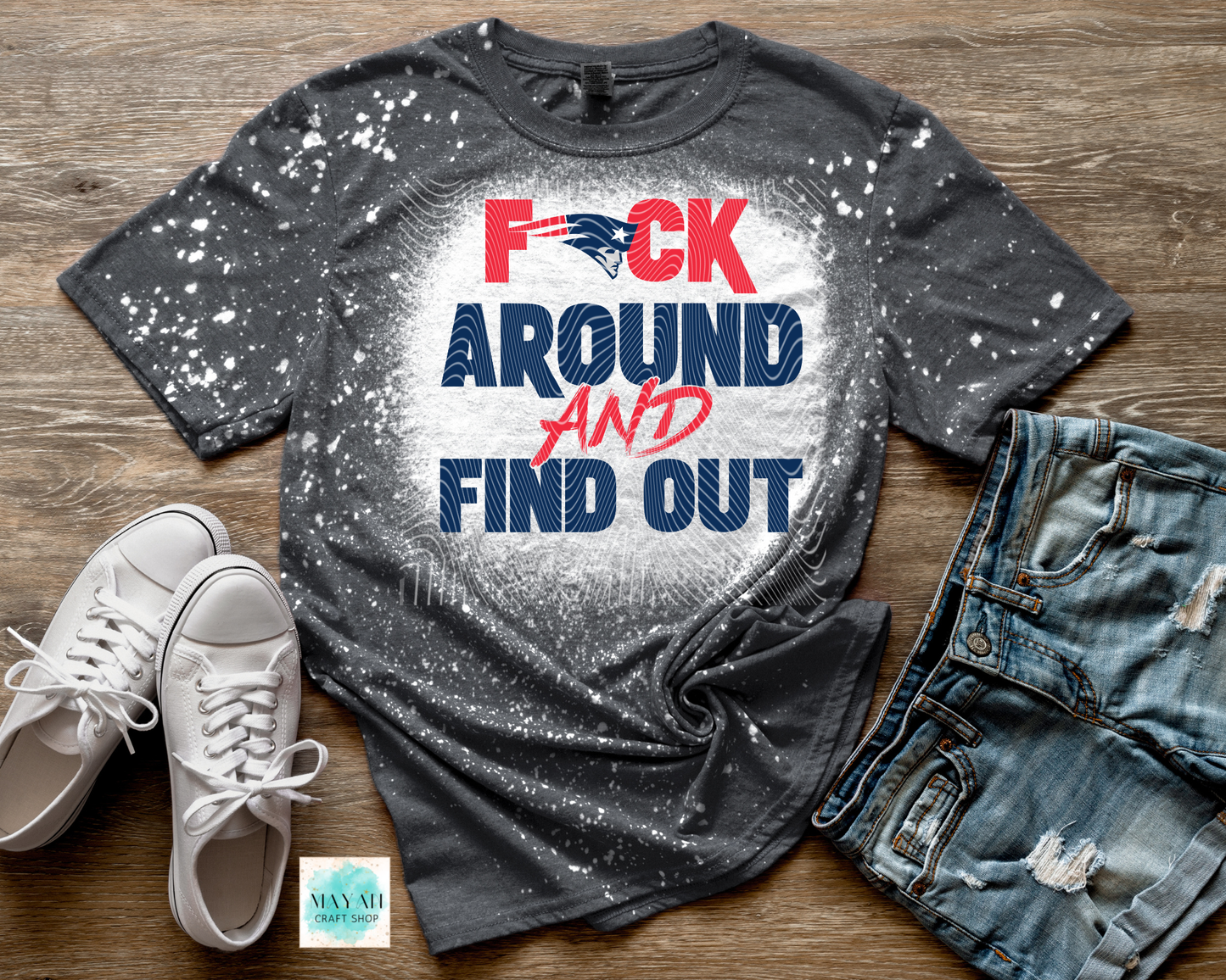Gray t-shirt with graphic text, white sneakers, and distressed jeans on a wooden surface