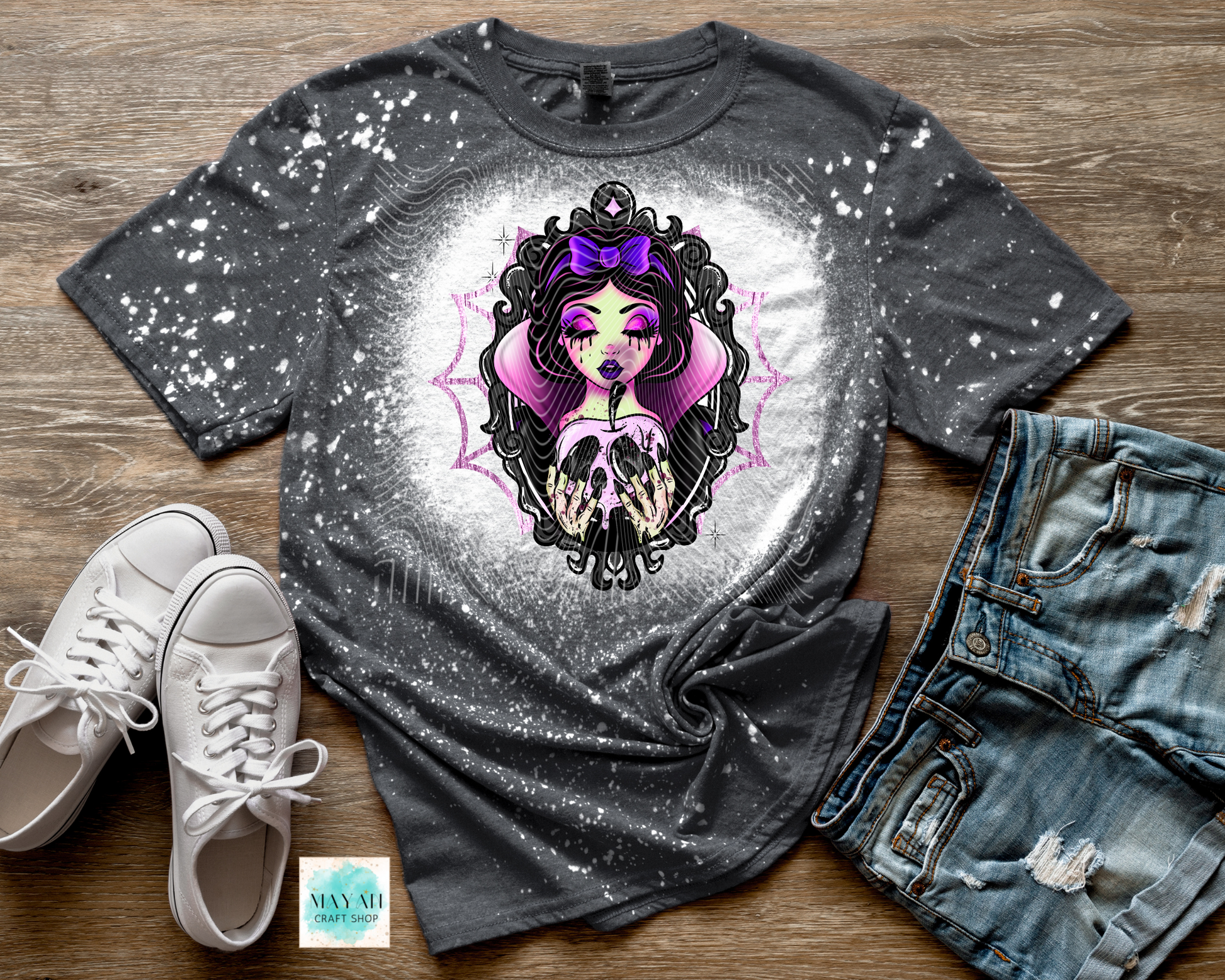 Gray t-shirt with a graphic design, white sneakers, and denim shorts on a wooden surface.