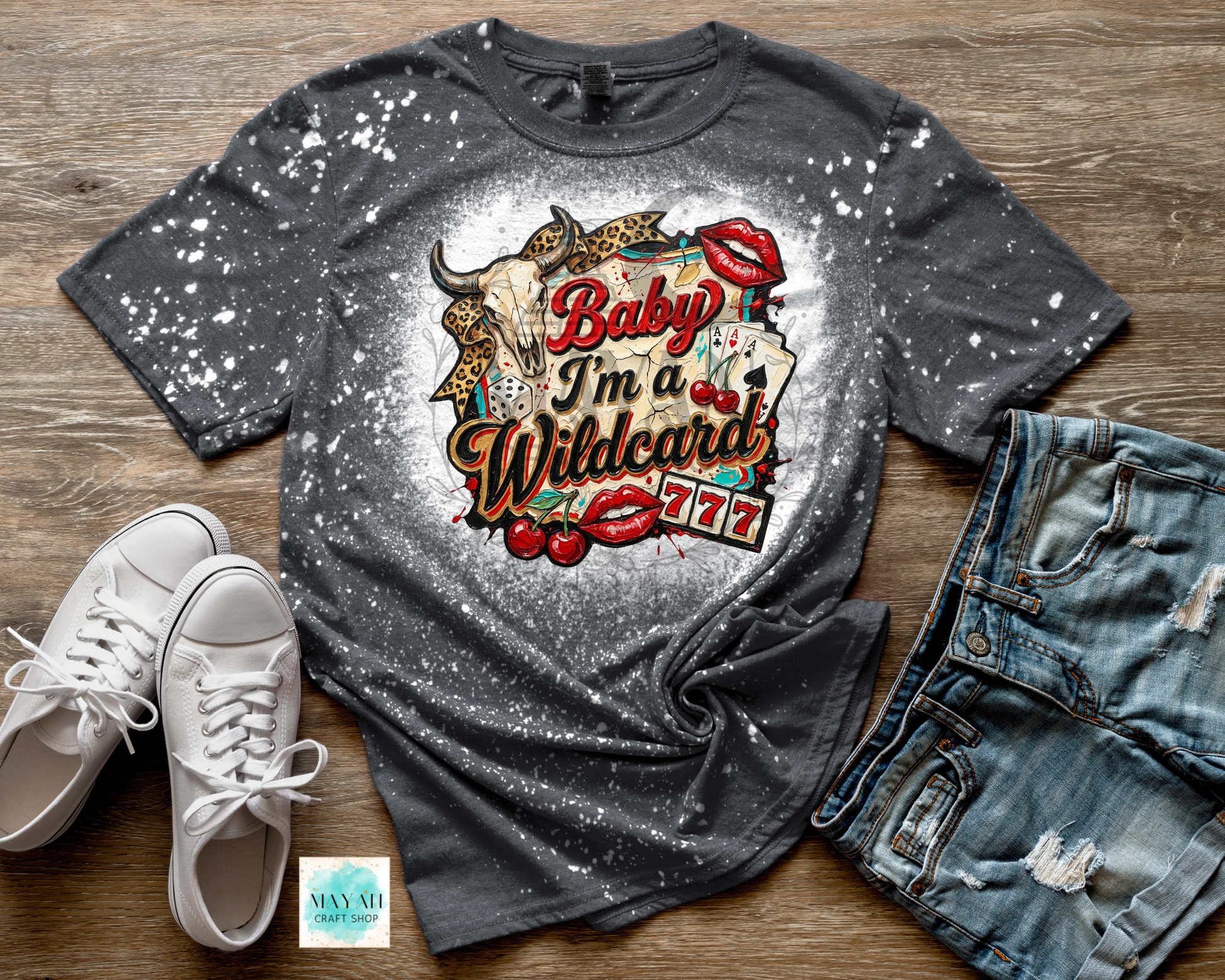Gray t-shirt with a graphic design featuring a bull and text, displayed with white sneakers and blue jeans on a wooden surface.
