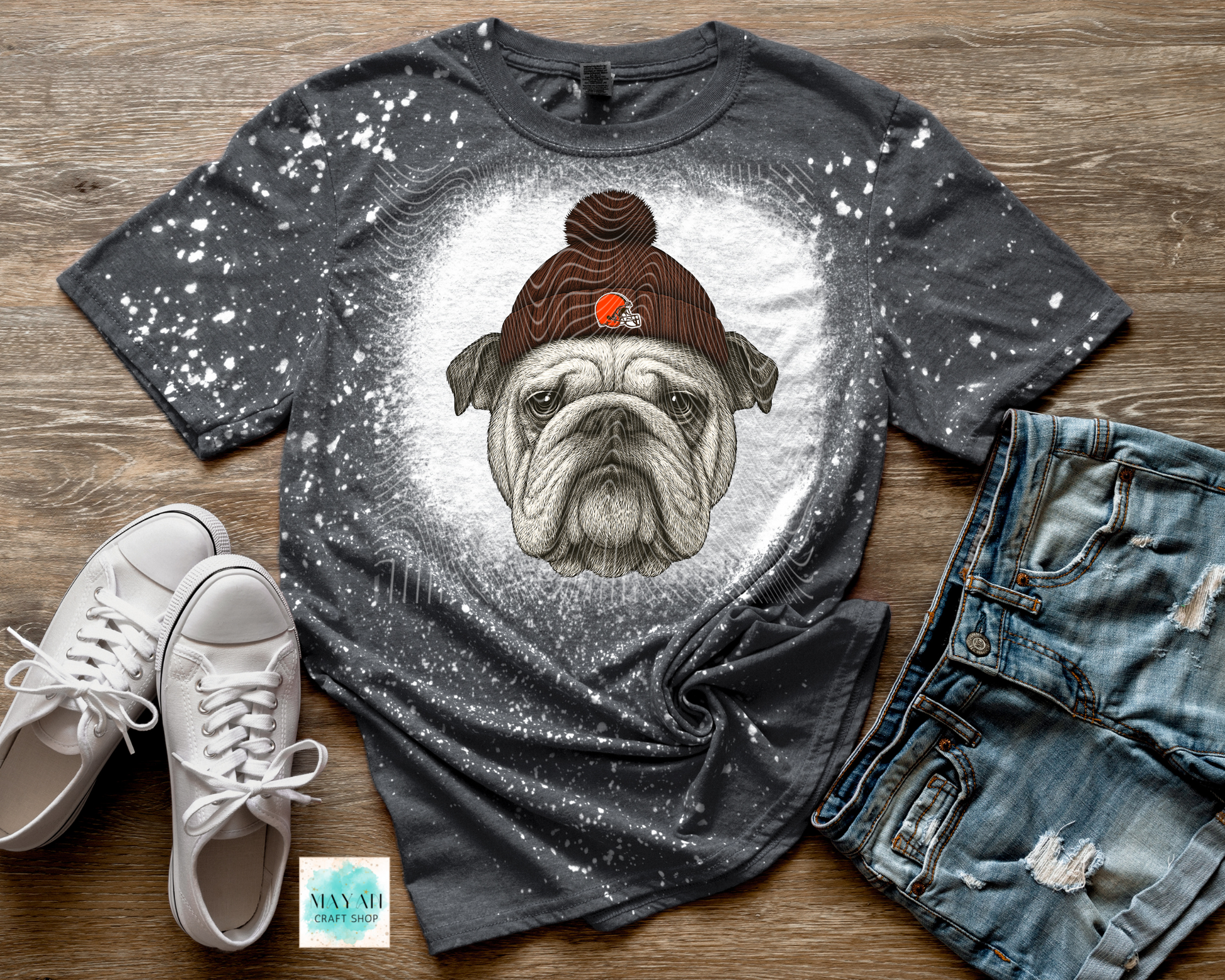 Gray t-shirt with a dog graphic and text, paired with white sneakers and jeans on a wooden surface.