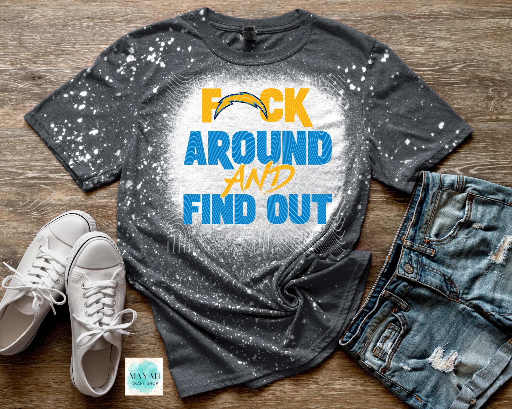 Gray t-shirt with sports team logo and text, paired with white sneakers and jeans on a wooden surface.