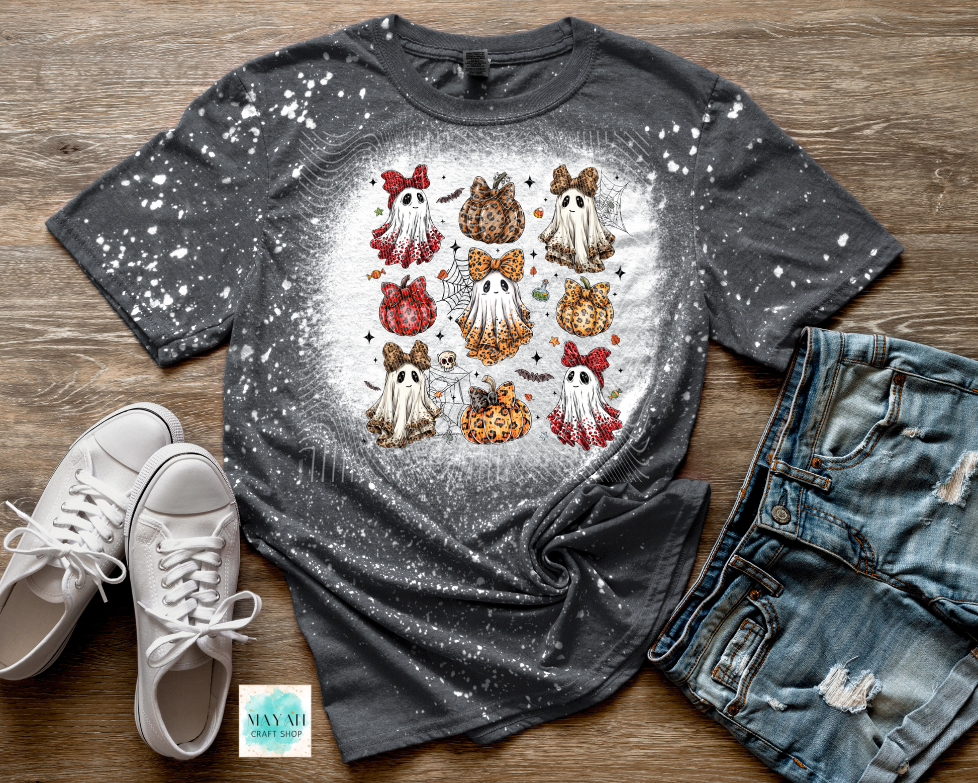 Gray t-shirt with ghost and pumpkin design on a wooden surface with white sneakers and jeans.
