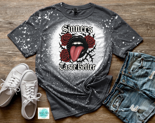 Gray t-shirt with graphic design and text, paired with white sneakers and jeans on a wooden surface.