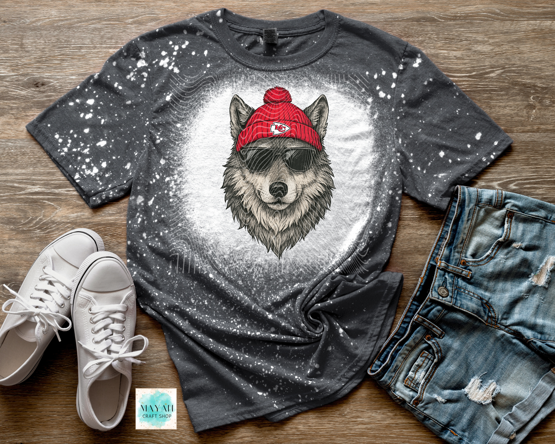 Gray t-shirt with wolf graphic wearing a red beanie, paired with white sneakers and jeans on a wooden surface.