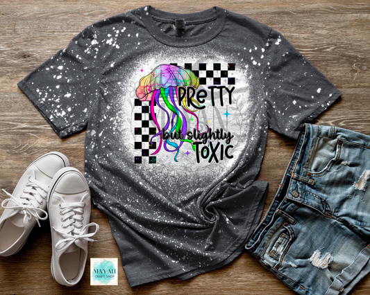 Gray bleached t-shirt with colorful jellyfish graphic and text, paired with white sneakers and jeans on a wooden surface.