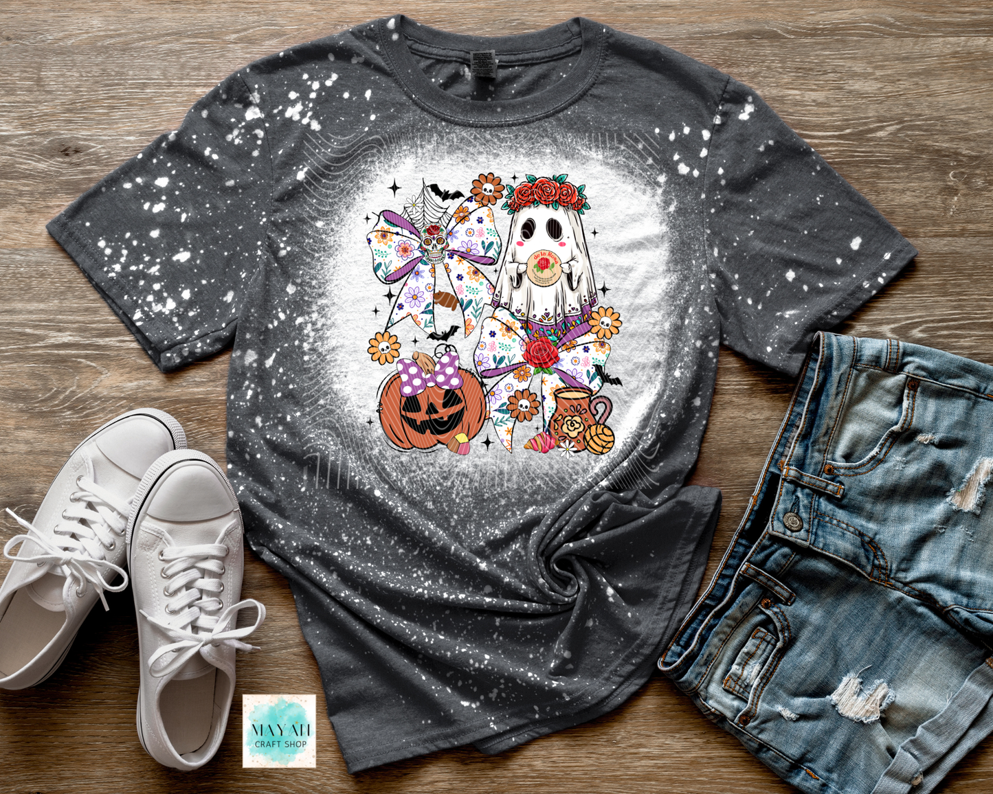 Gray t-shirt with Halloween-themed design on a wooden surface with shoes and jeans.