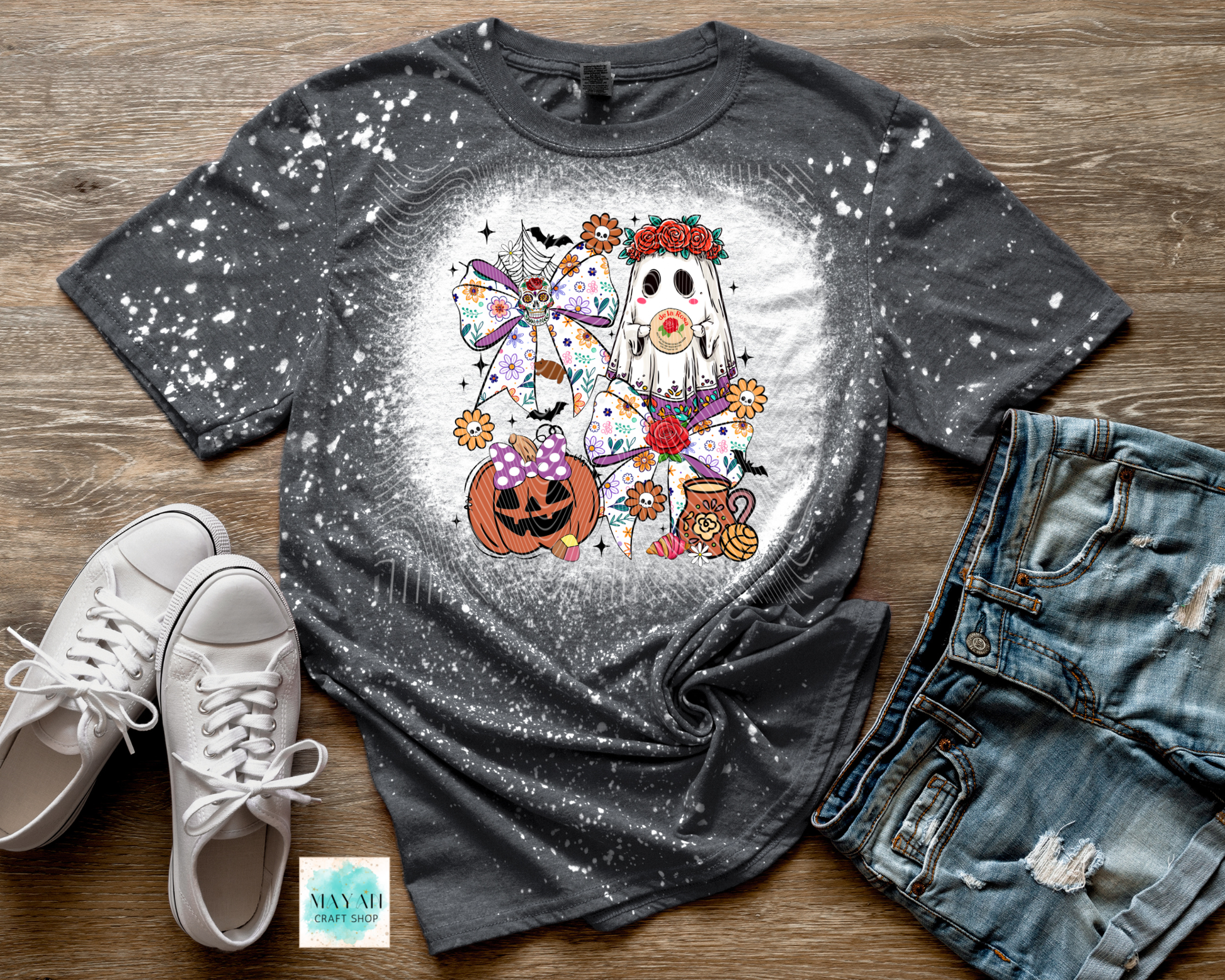 Gray t-shirt with Halloween-themed design on a wooden surface with shoes and jeans.