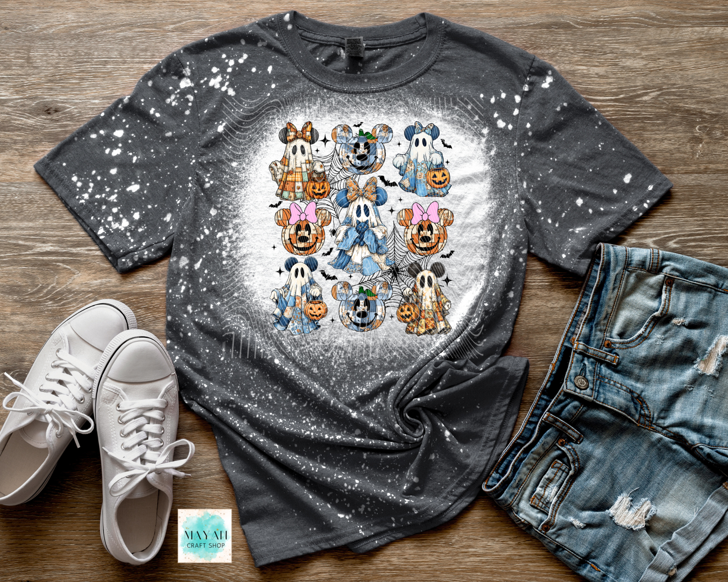 Gray t-shirt with cartoon character design on a wooden surface with sneakers and jeans.