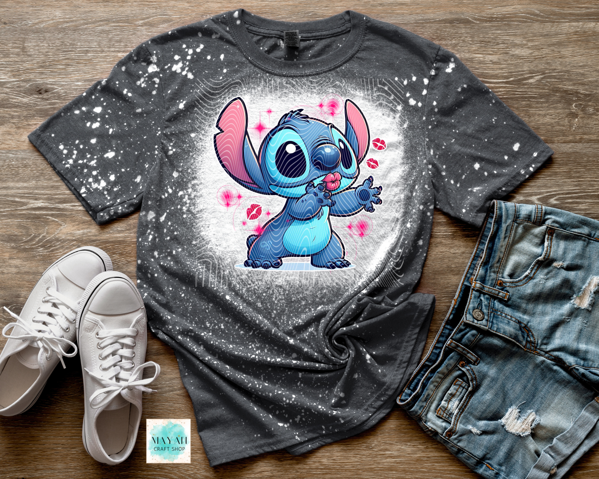 Gray t-shirt with cartoon character, white sneakers, and denim shorts on a wooden surface