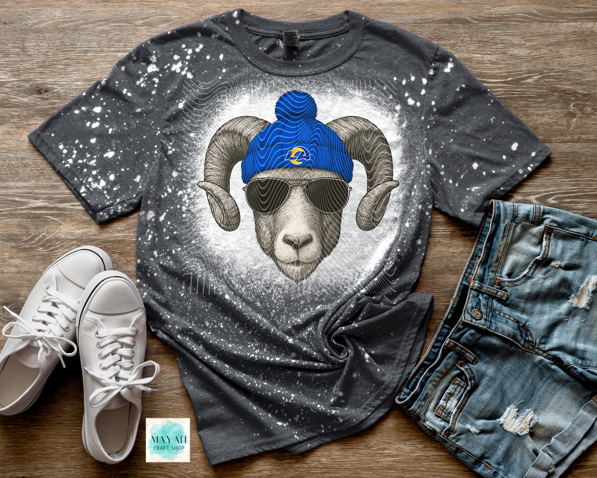 Gray t-shirt with ram graphic wearing a blue beanie, paired with white sneakers and jeans on a wooden surface.