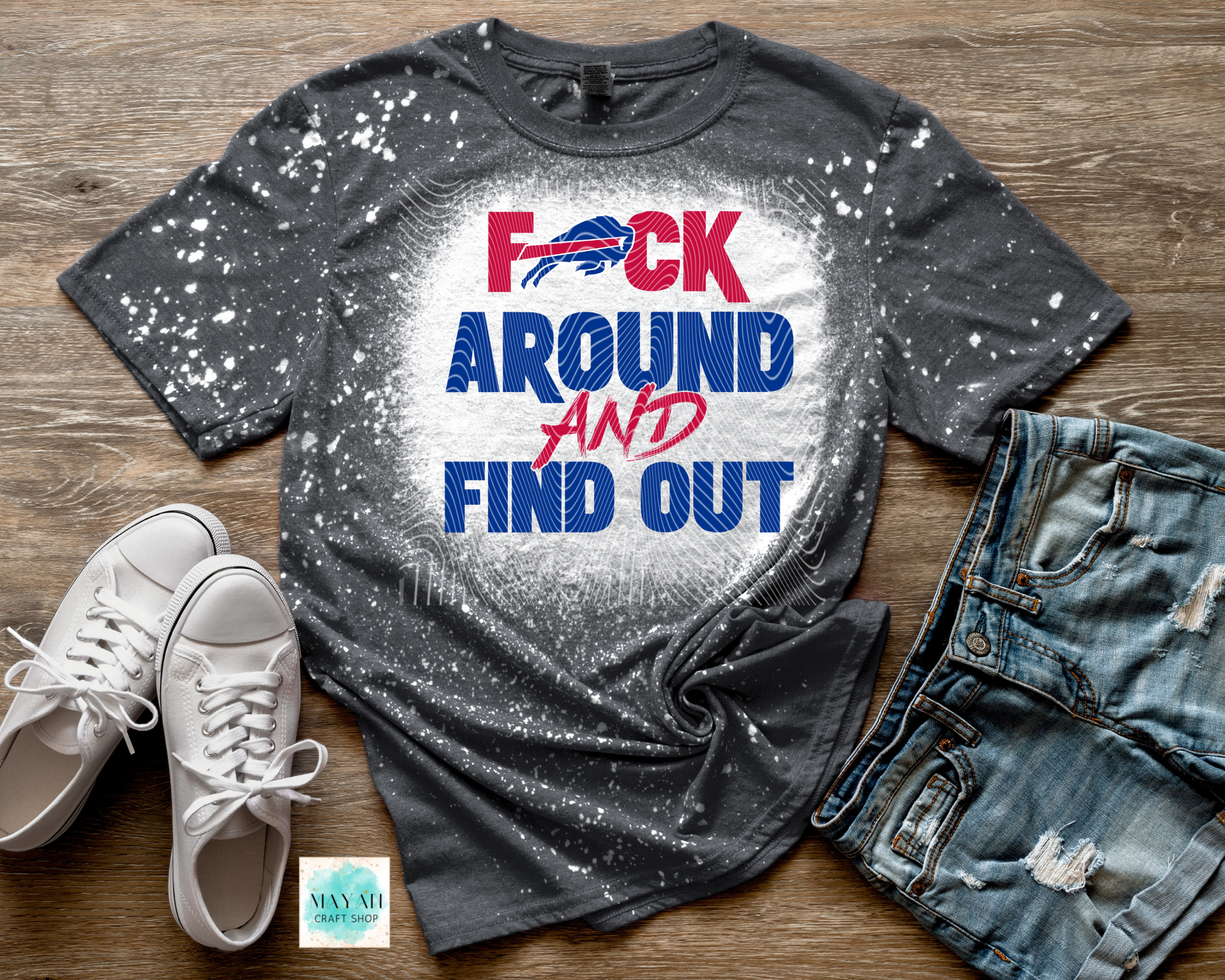 Gray t-shirt with colorful text, white sneakers, and jeans on a wooden surface