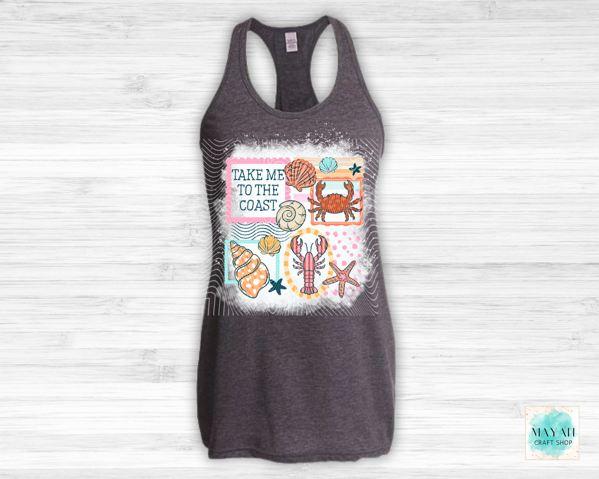 Gray tank top with coastal design and text 'Take Me to the Coast' on a light wooden background.