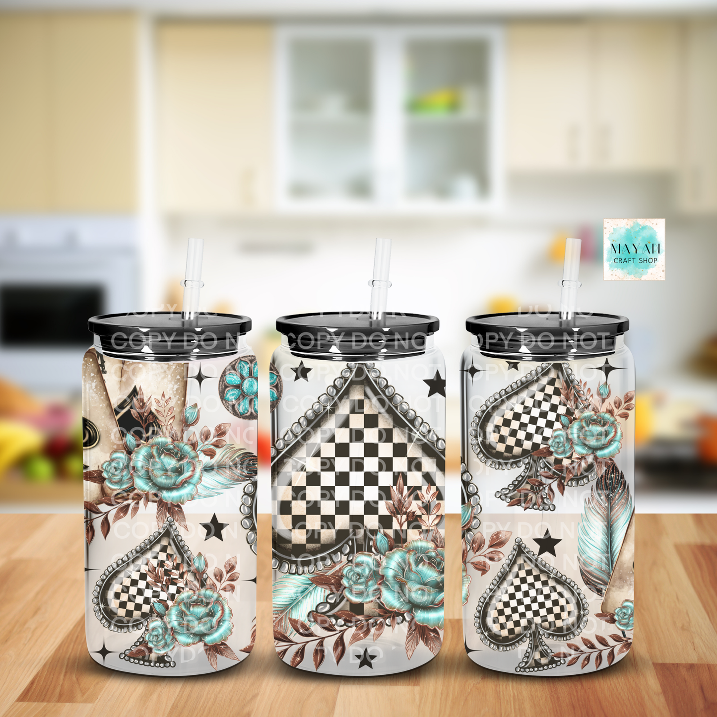 Three tumblers with decorative designs on a wooden surface in a kitchen setting.