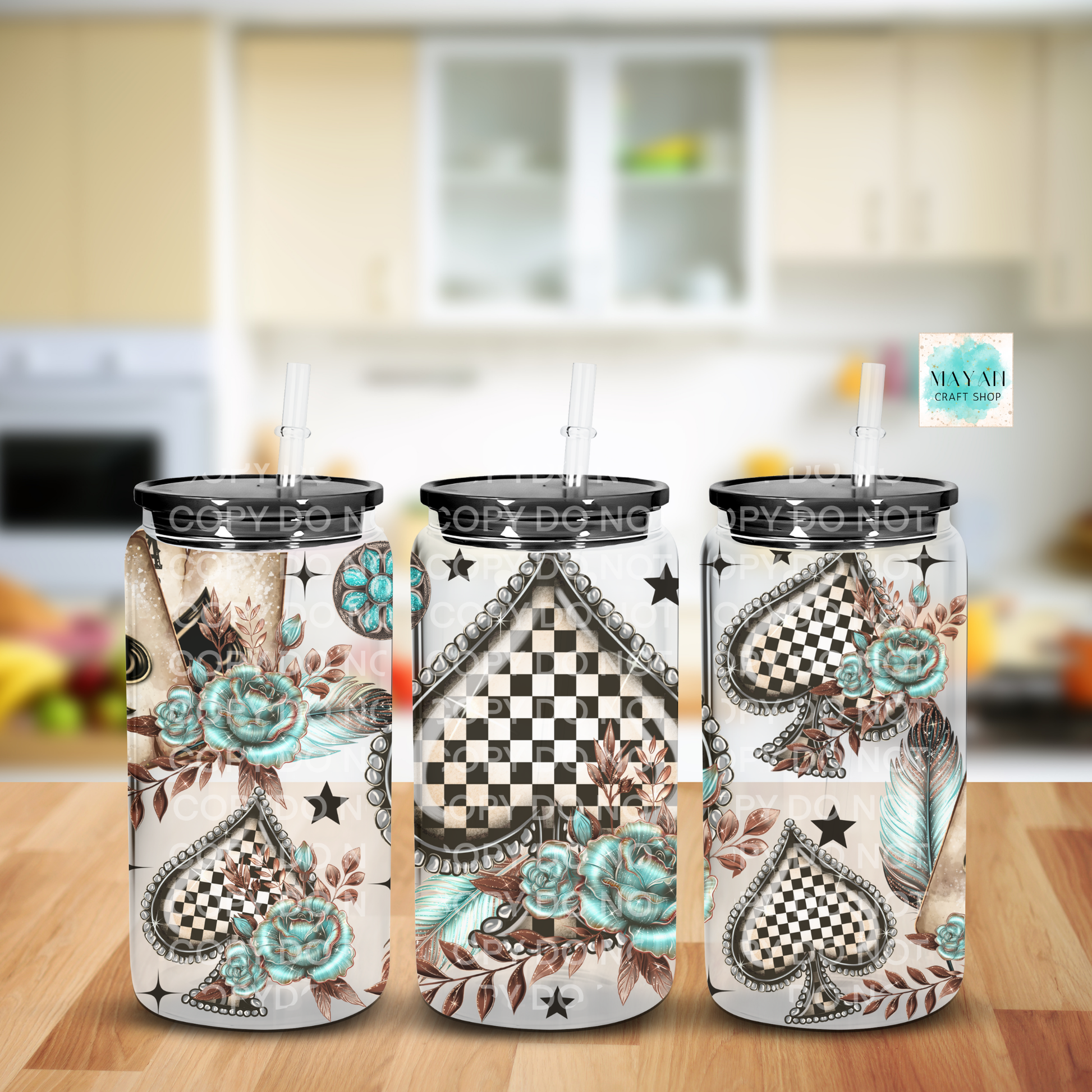 Three tumblers with decorative designs on a wooden surface in a kitchen setting.