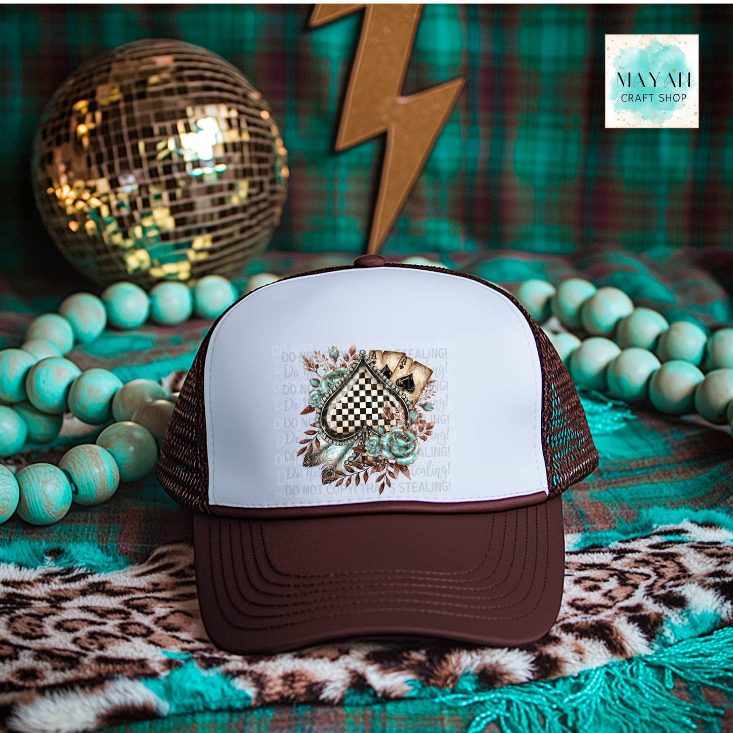 Brown and white cap with a decorative design on a colorful background with beads and a disco ball.