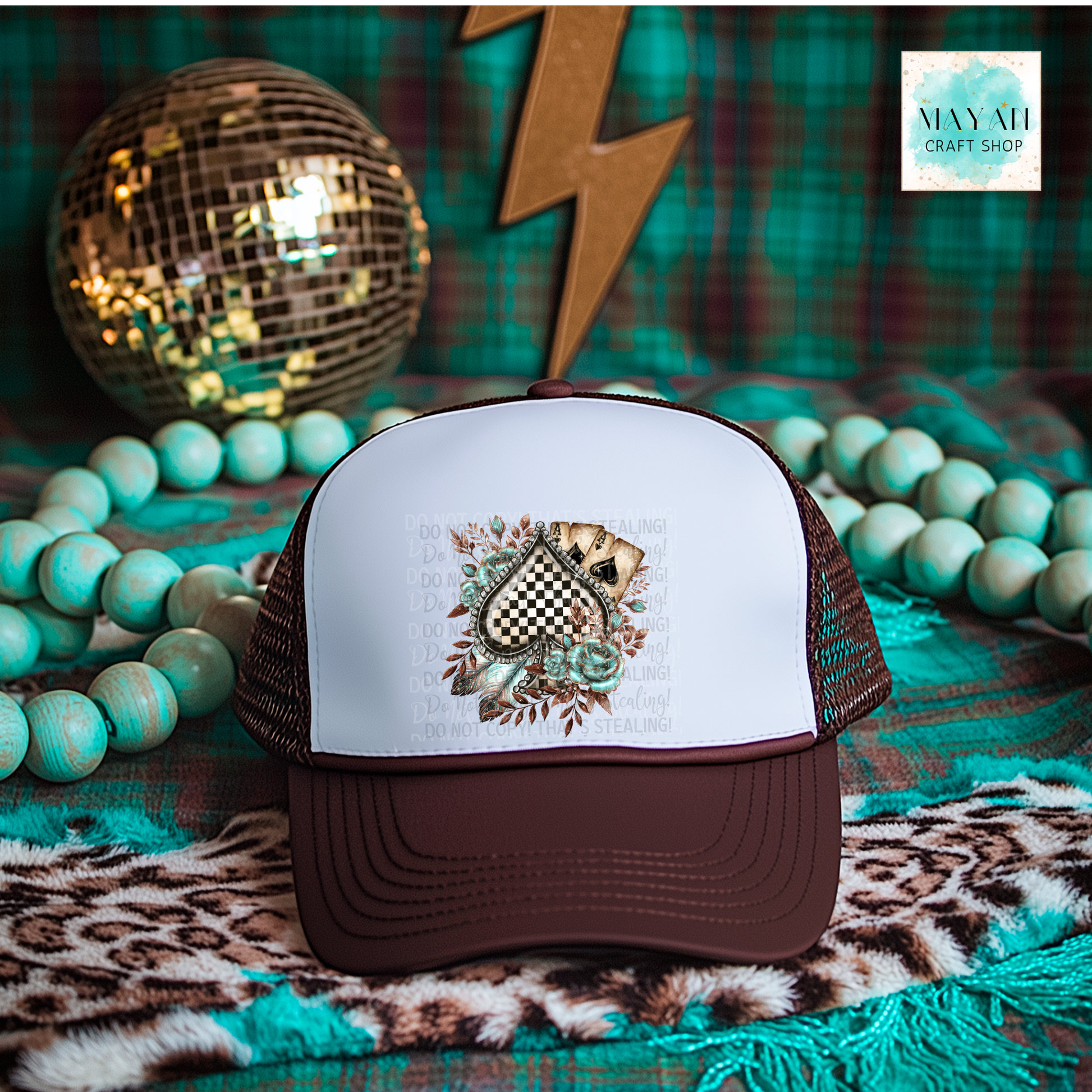 Brown and white cap with a decorative design on a colorful background with beads and a disco ball.