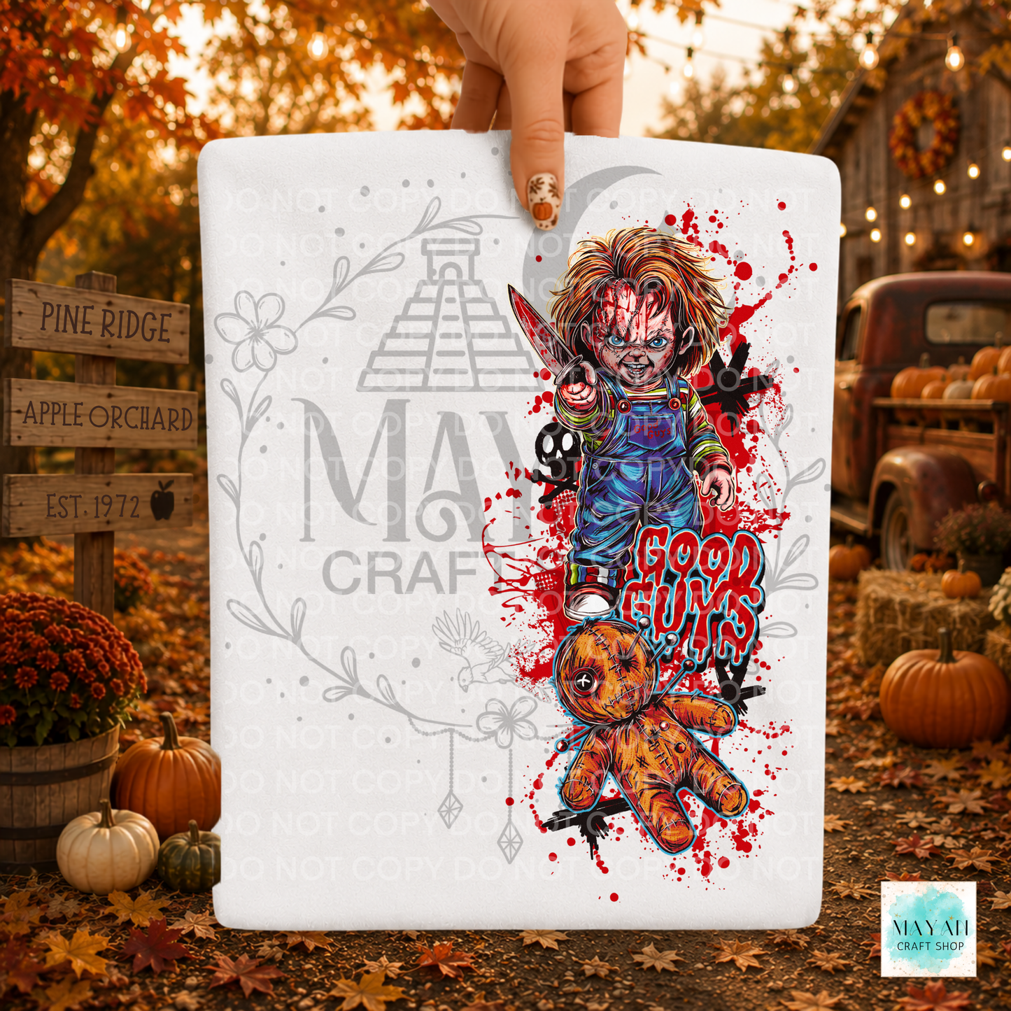 A hand holds a white rectangular sign featuring a horror-themed graphic of Chucky with a knife, a teddy bear, skulls. 