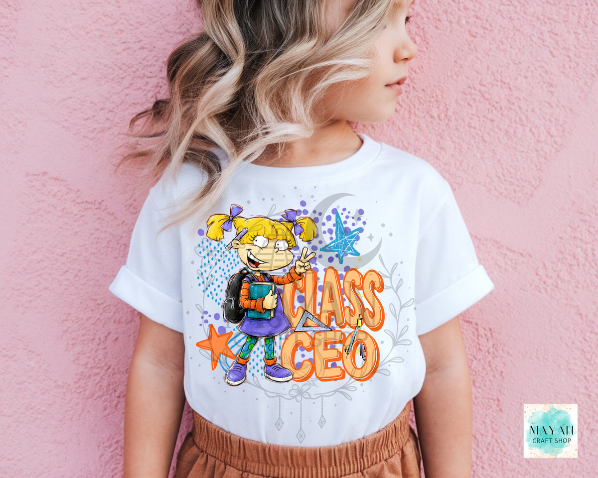A child wearing a white graphic t-shirt with a cartoon character and the words 'CLASS CEO' in orange, posed against a pink textured wall.