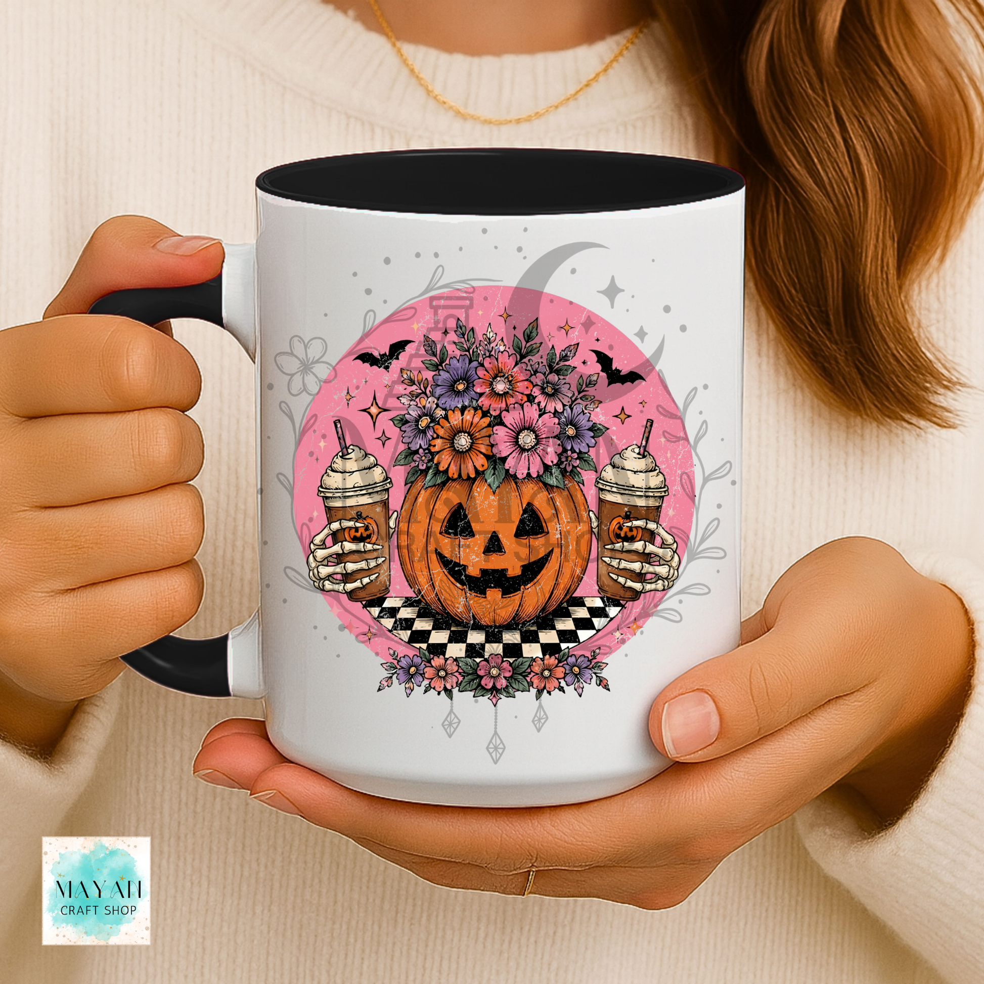 Person holding a mug with a Halloween-themed design featuring a pumpkin, flowers, and potion bottles.