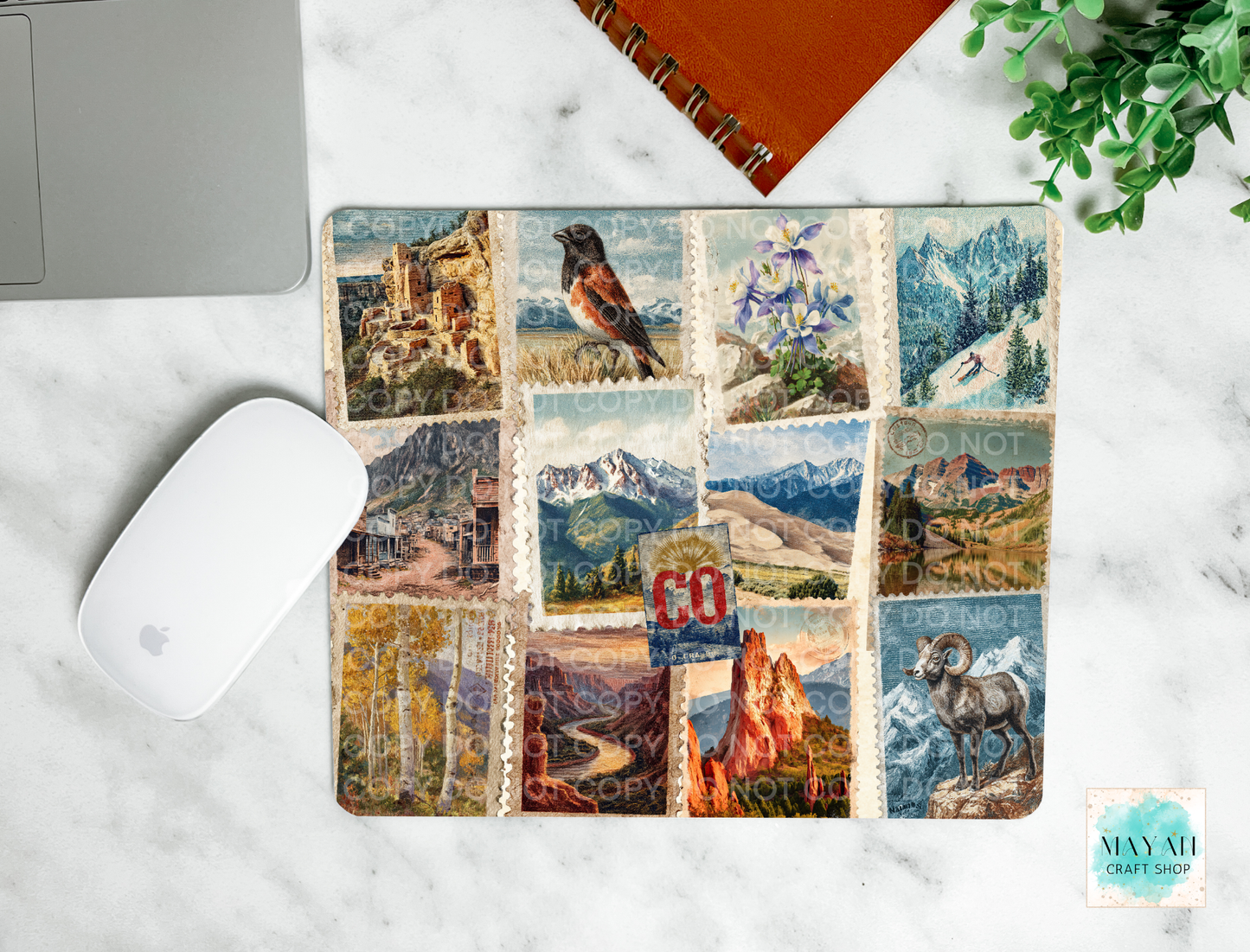 Mouse pad with nature-themed cover on a marble surface with a laptop and mouse.