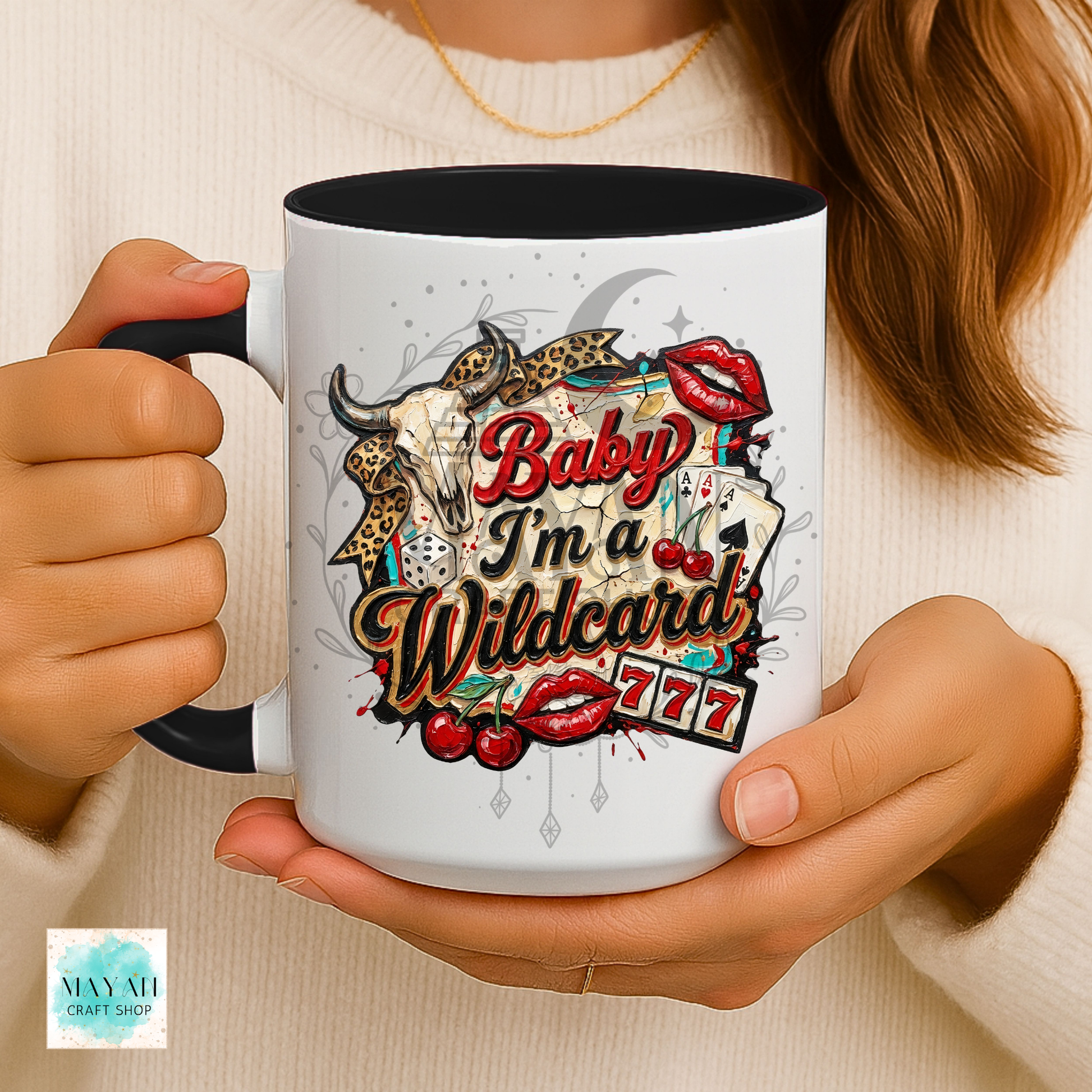 Person holding a mug with a colorful design and text 'Baby I'm a Wildcard' on a beige background.