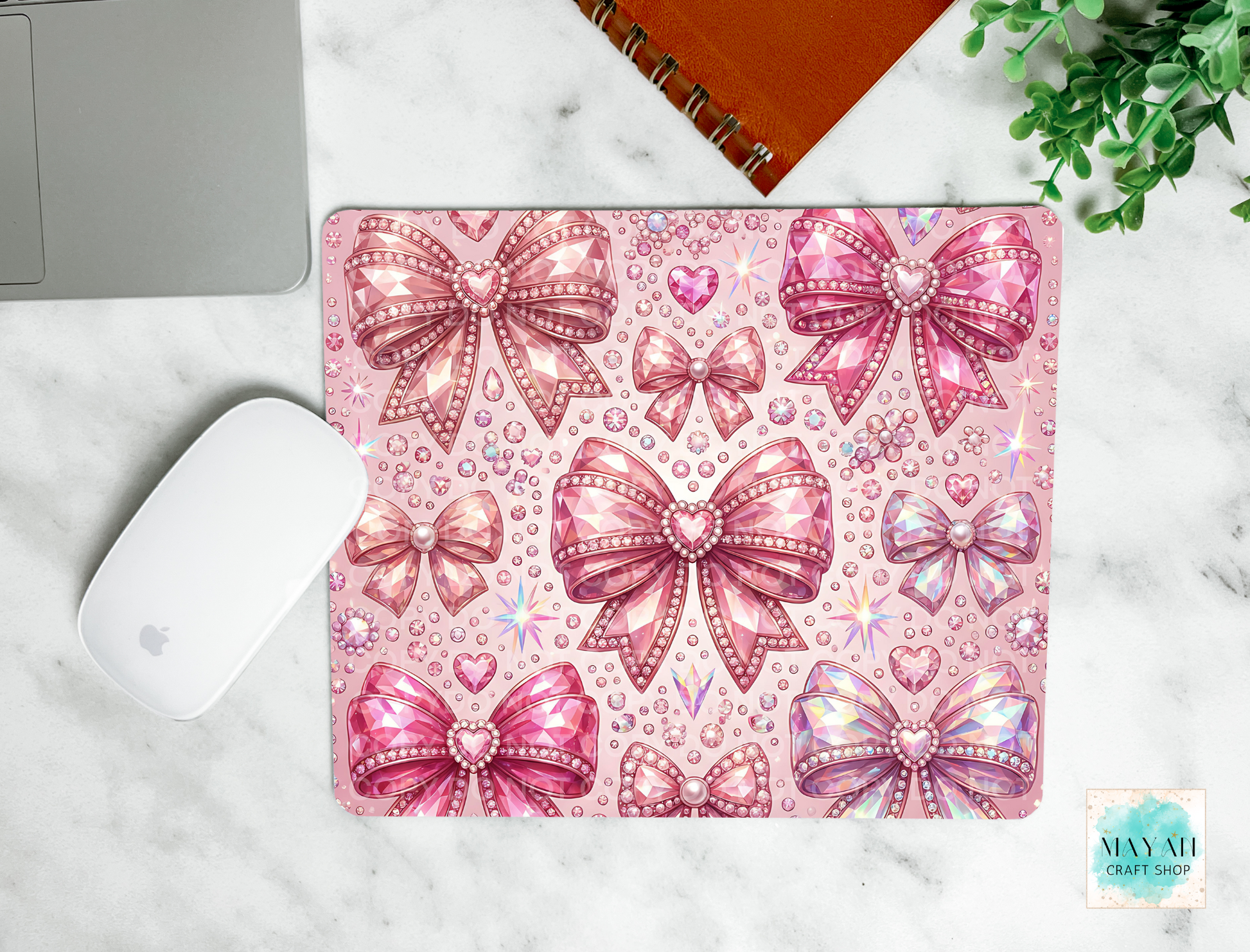 Pink bow patterned mouse pad on a marble surface with a laptop and mouse.
