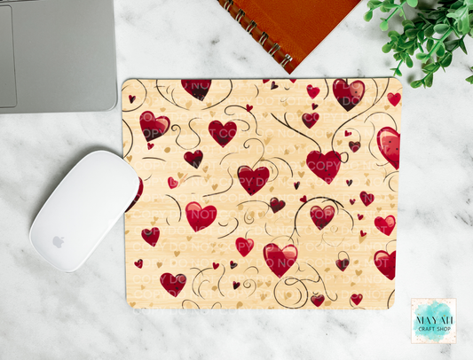 Heart-patterned mouse pad on a marble surface with a laptop and mouse.