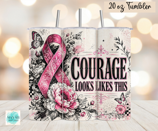 Three 20 oz tumblers with metal straws displayed side-by-side on a light wood surface against a warm bokeh background. The tumblers feature a floral and ribbon design with a pink awareness ribbon, black and white flowers, butterflies, and the text 'COURAGE LOOKS LIKES THIS'.