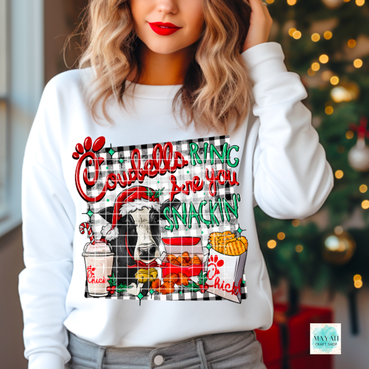 Person wearing a white sweatshirt with colorful graphic design in front of a Christmas tree.