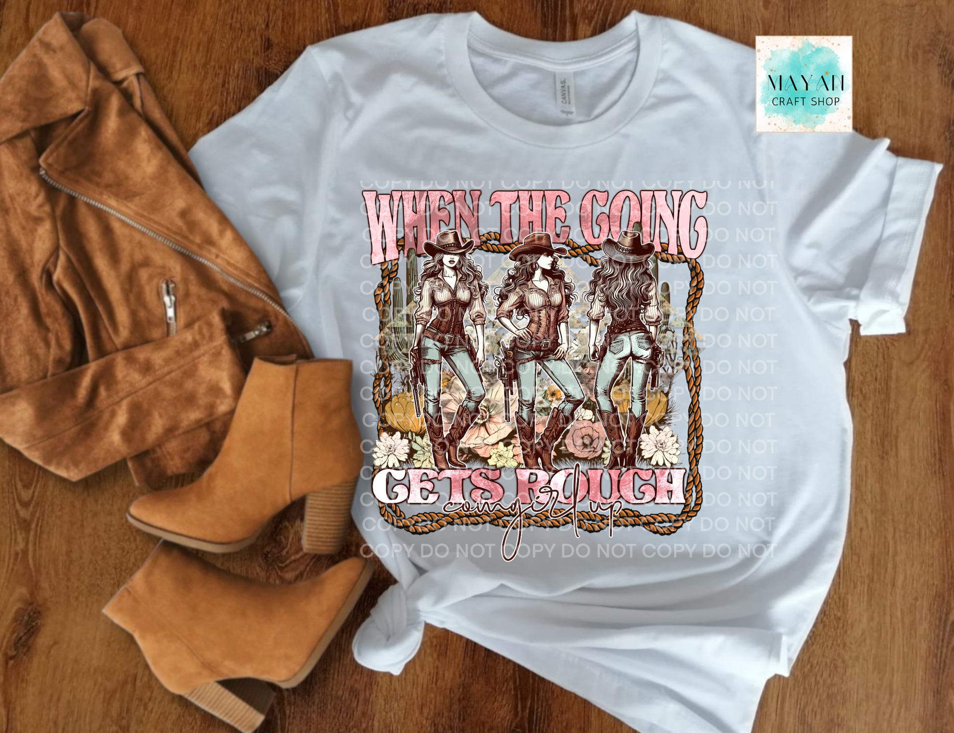 White t-shirt with graphic design and text on a wooden surface with boots and a jacket.